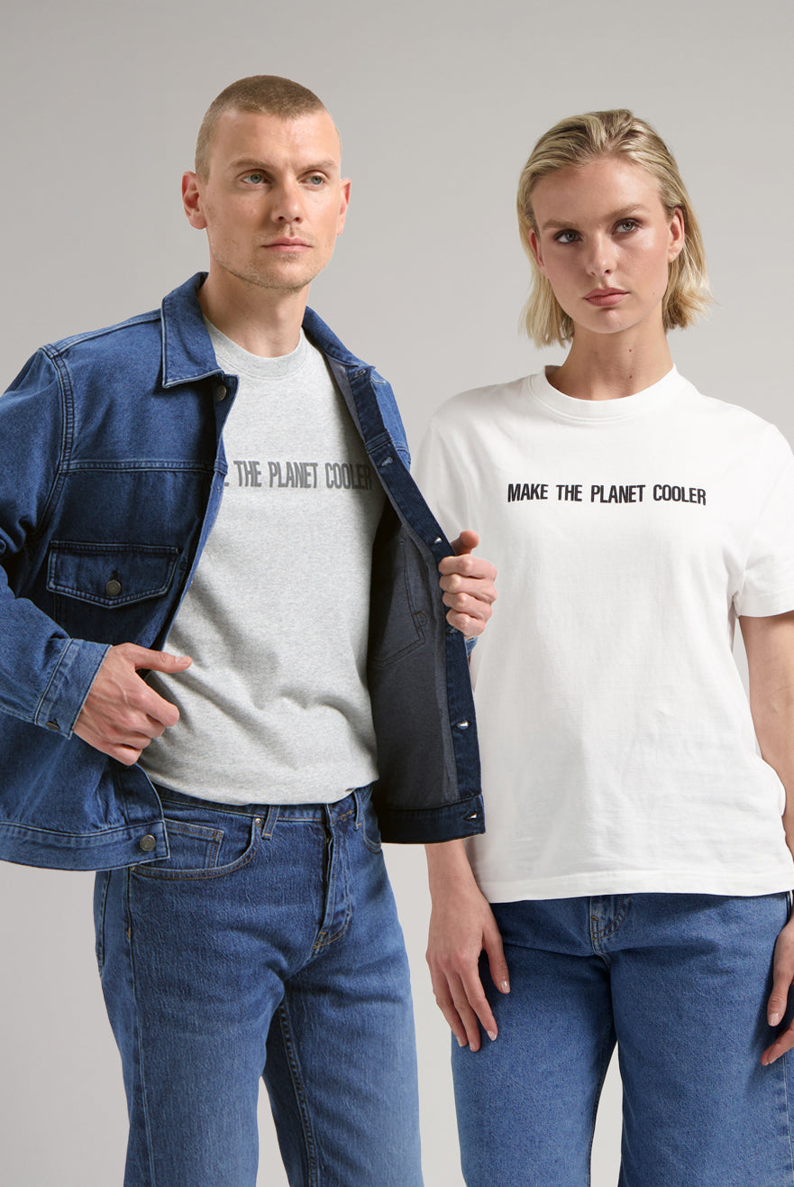 Sustainable MUD Jeans in classic blue denim with utility pockets, paired with a matching blue jacket and white sneakers.