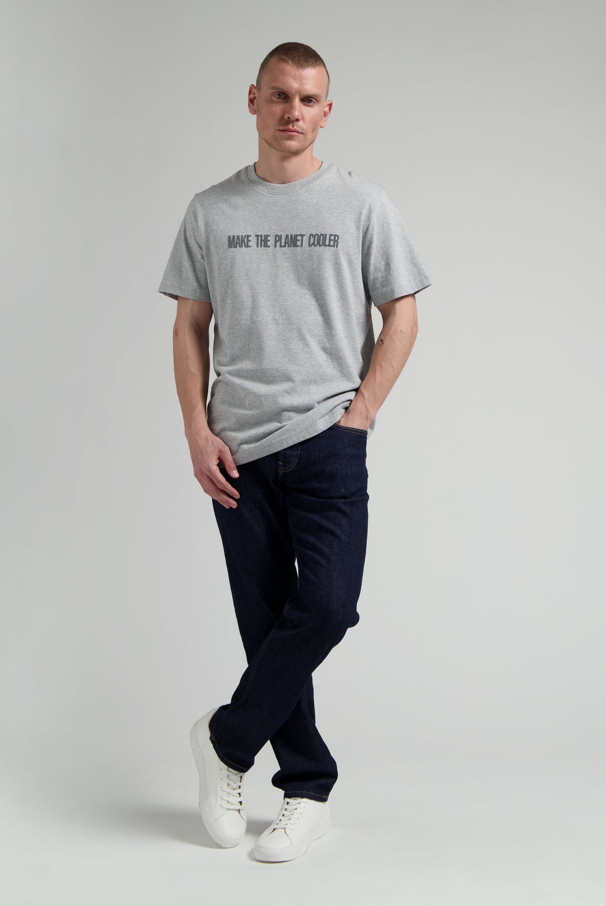 Sustainable MUD Jeans in classic blue denim, crafted from ethical materials, paired with a simple black tee and white sneakers.