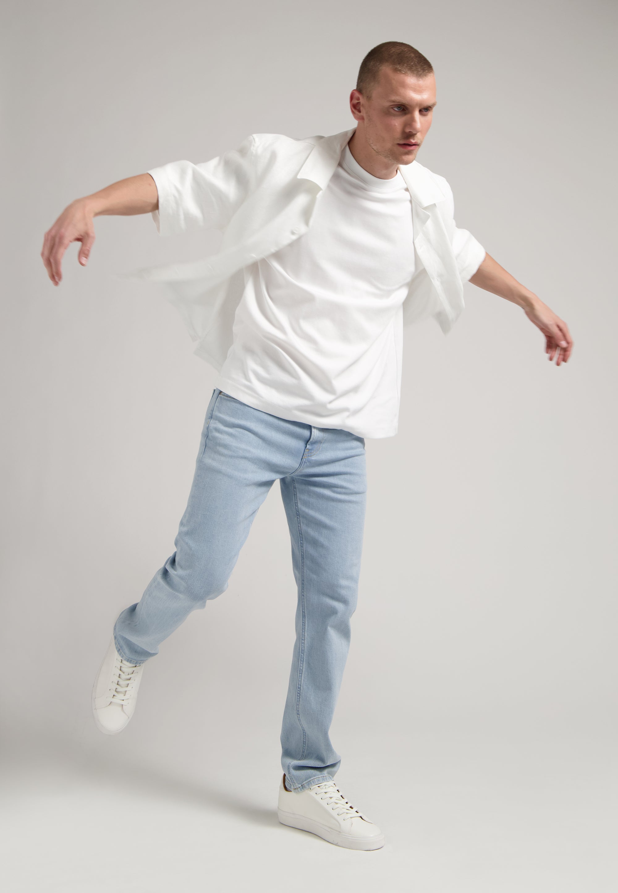 Sustainable MUD Jeans in deep blue denim, crafted for an ethical wardrobe, shown with white sneakers.