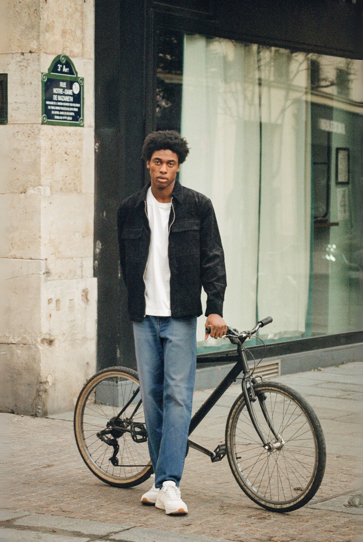 Sustainable MUD Jeans in deep blue denim, crafted from organic cotton, worn with a gray sweater and white sneakers.