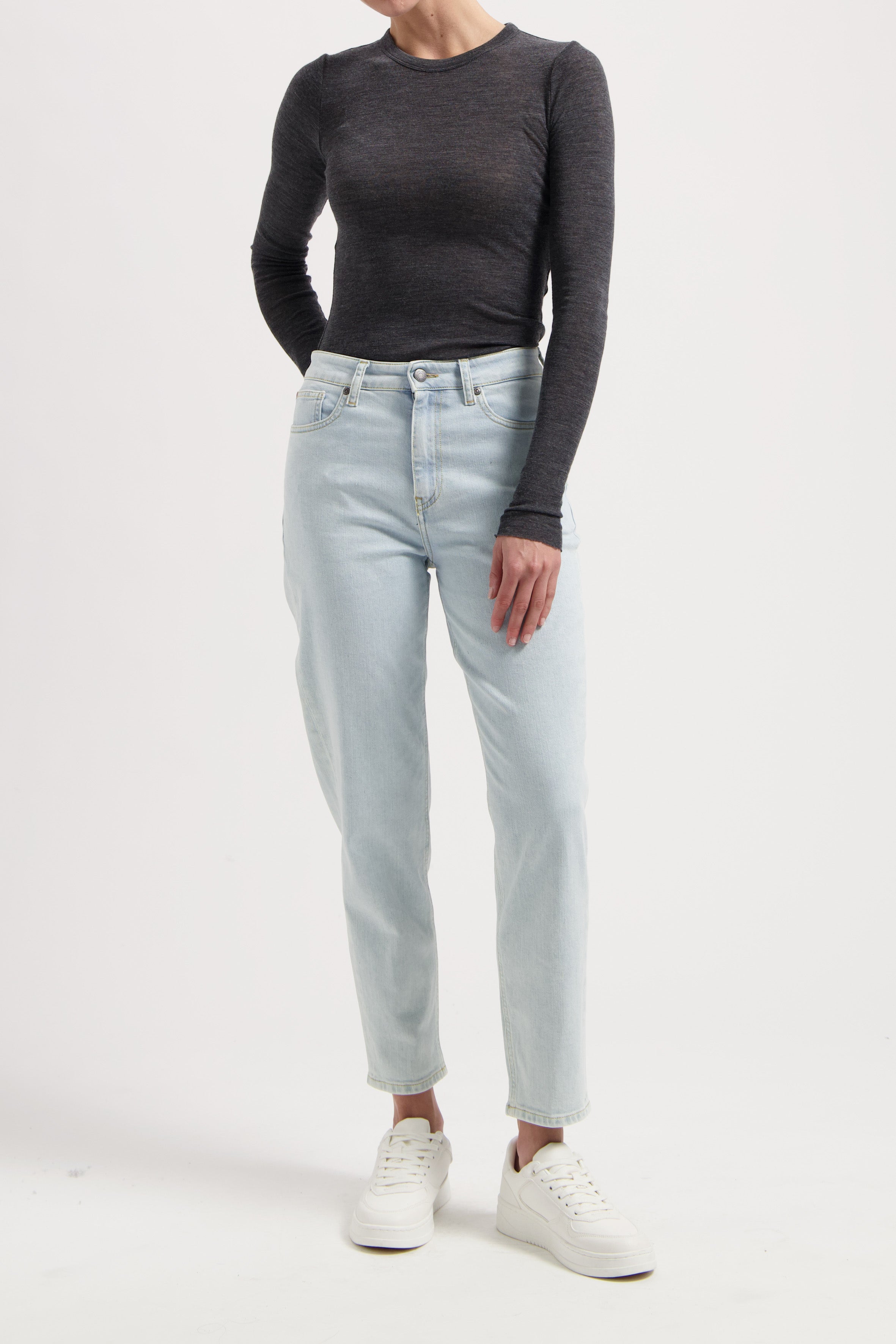 Casual outfit showcasing light blue high-waisted jeans paired with a dark gray long-sleeve top and white sneakers.