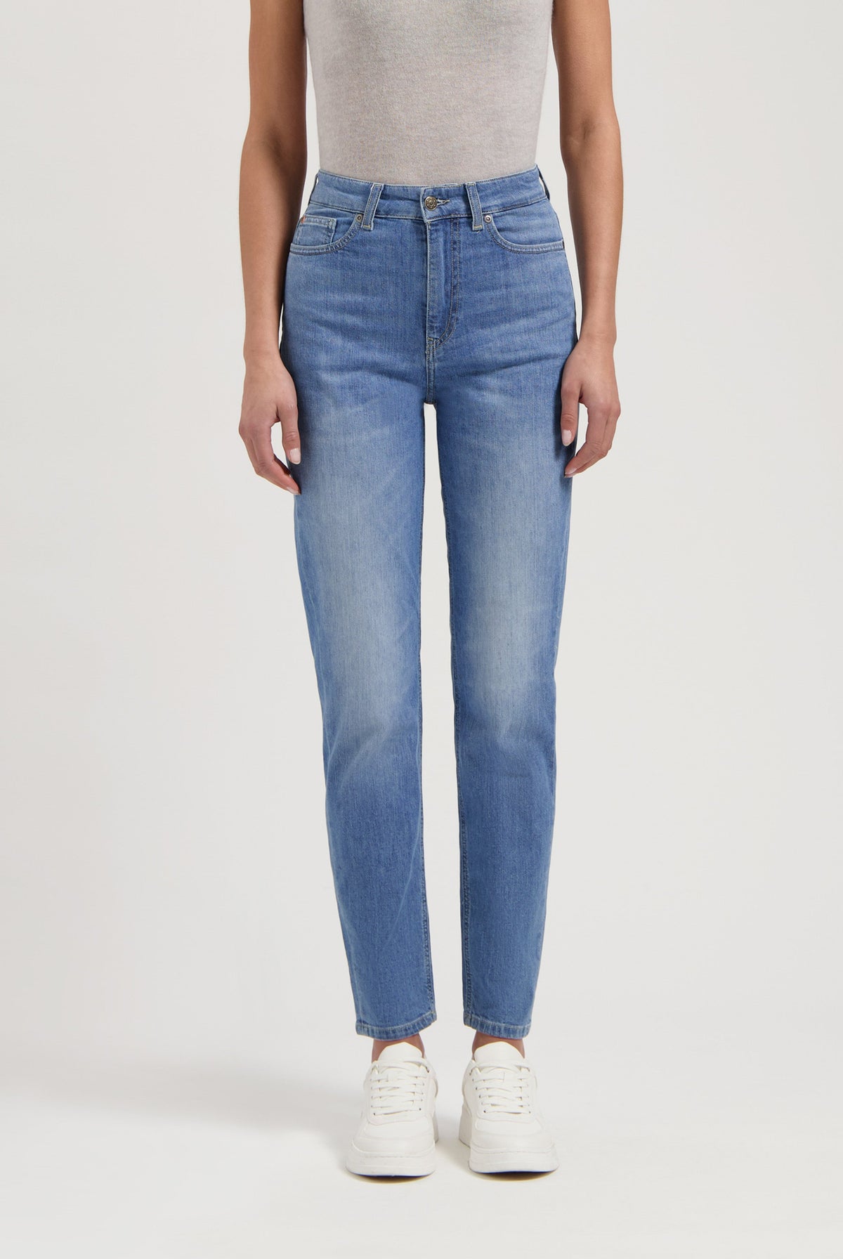 Casual blue jeans with high waist fit paired with a light gray sleeveless top and white sneakers for a relaxed look.