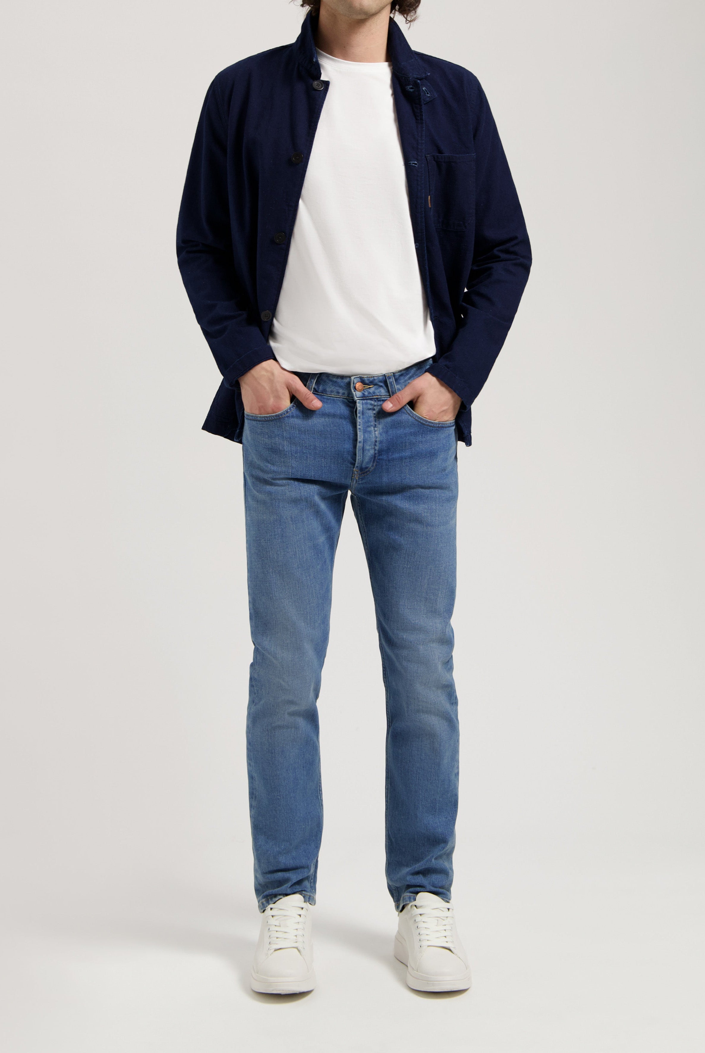 Sustainable MUD Jeans in light blue denim, crafted from organic cotton, paired with a white sweater for a classic look.
