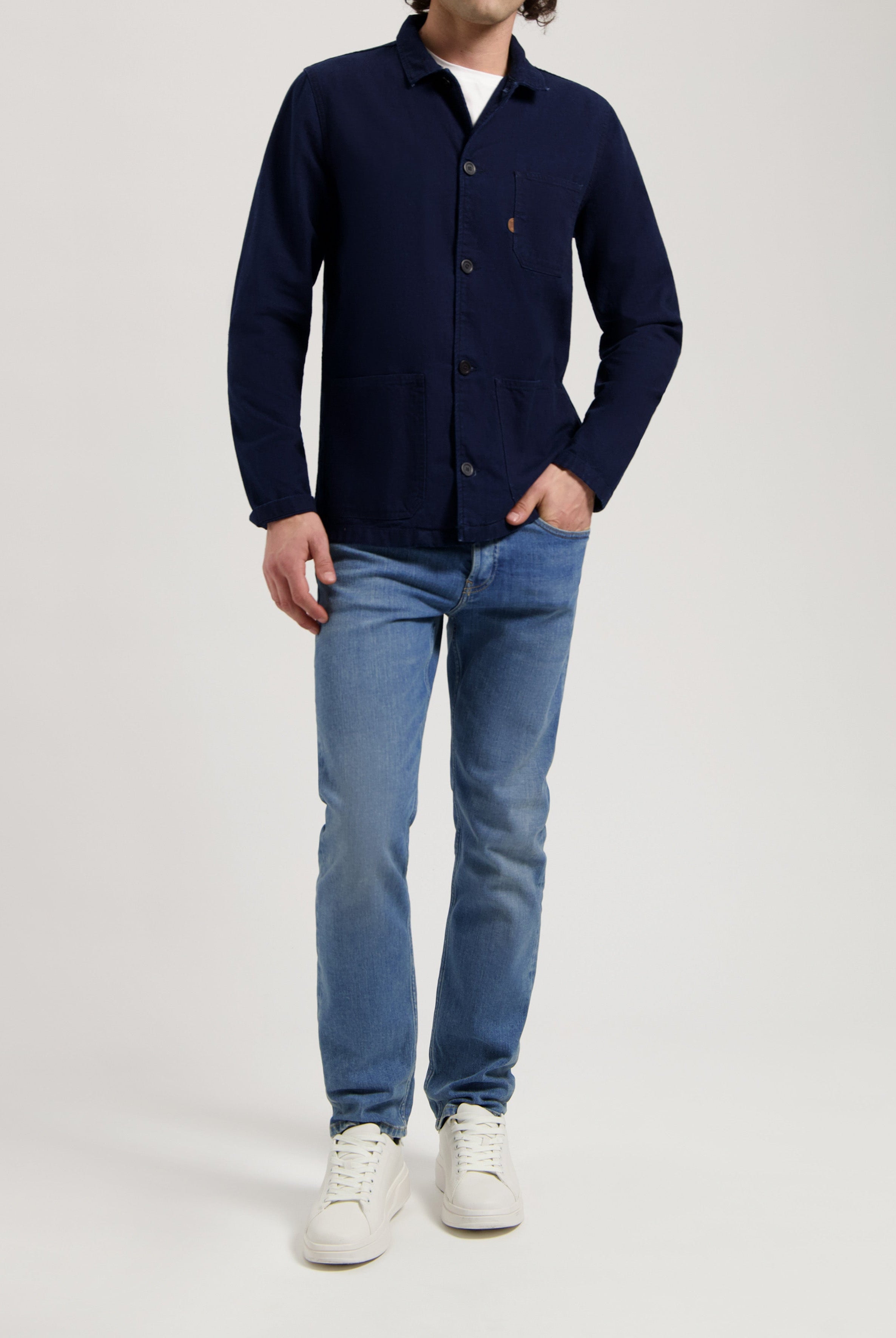 Sustainable MUD Jeans in light blue denim with a relaxed fit, paired with an ethical cream knit sweater.