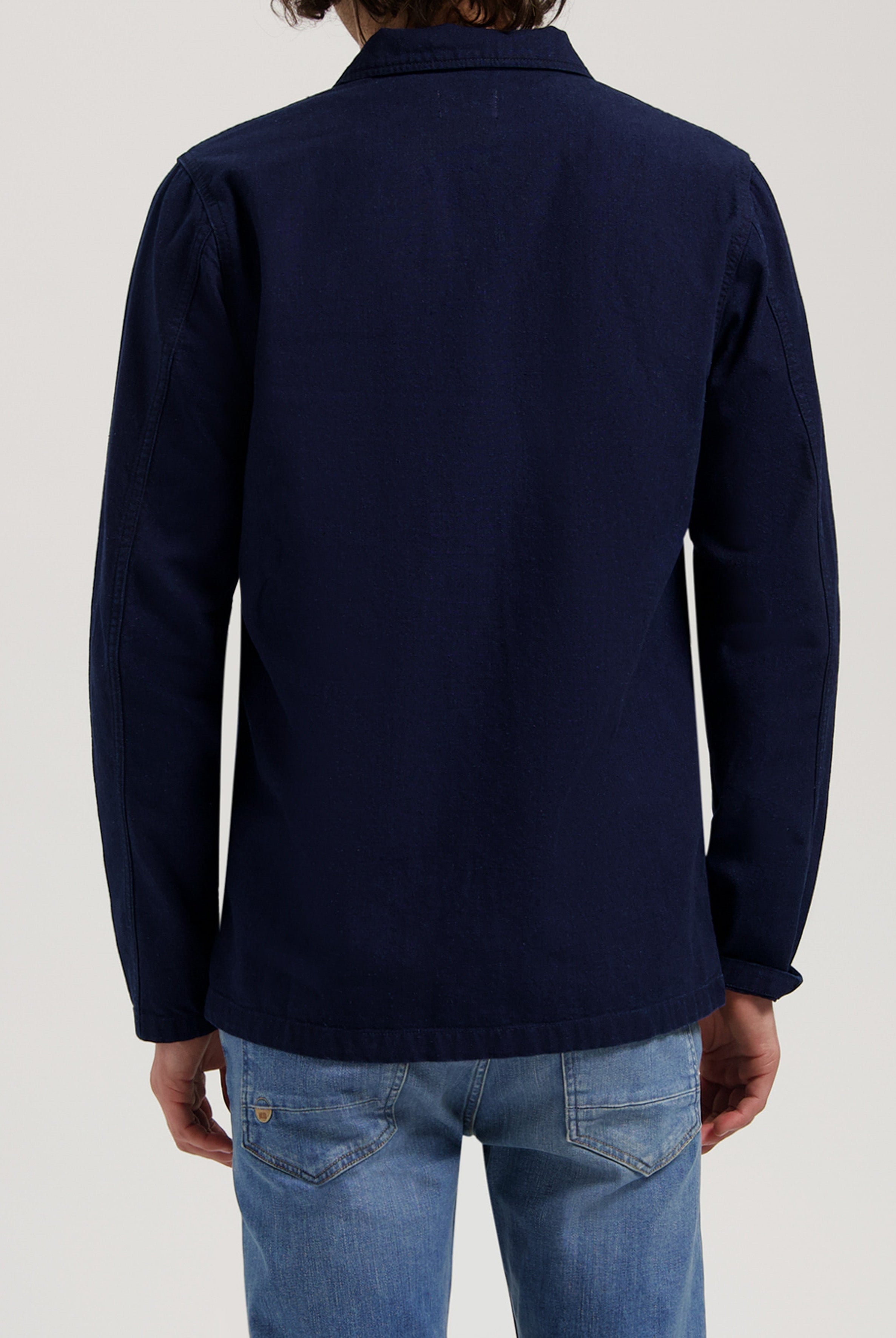 Sustainable MUD Jeans crafted from organic cotton, featuring blue denim in a relaxed fit, styled with a black jacket.