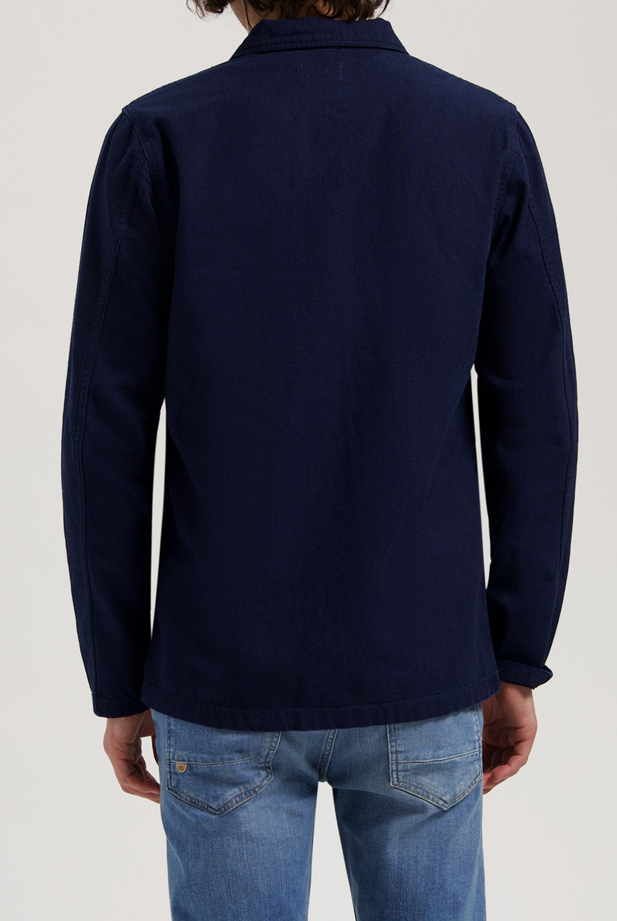 Sustainable MUD Jeans crafted from organic cotton, featuring blue denim in a relaxed fit, styled with a black jacket.