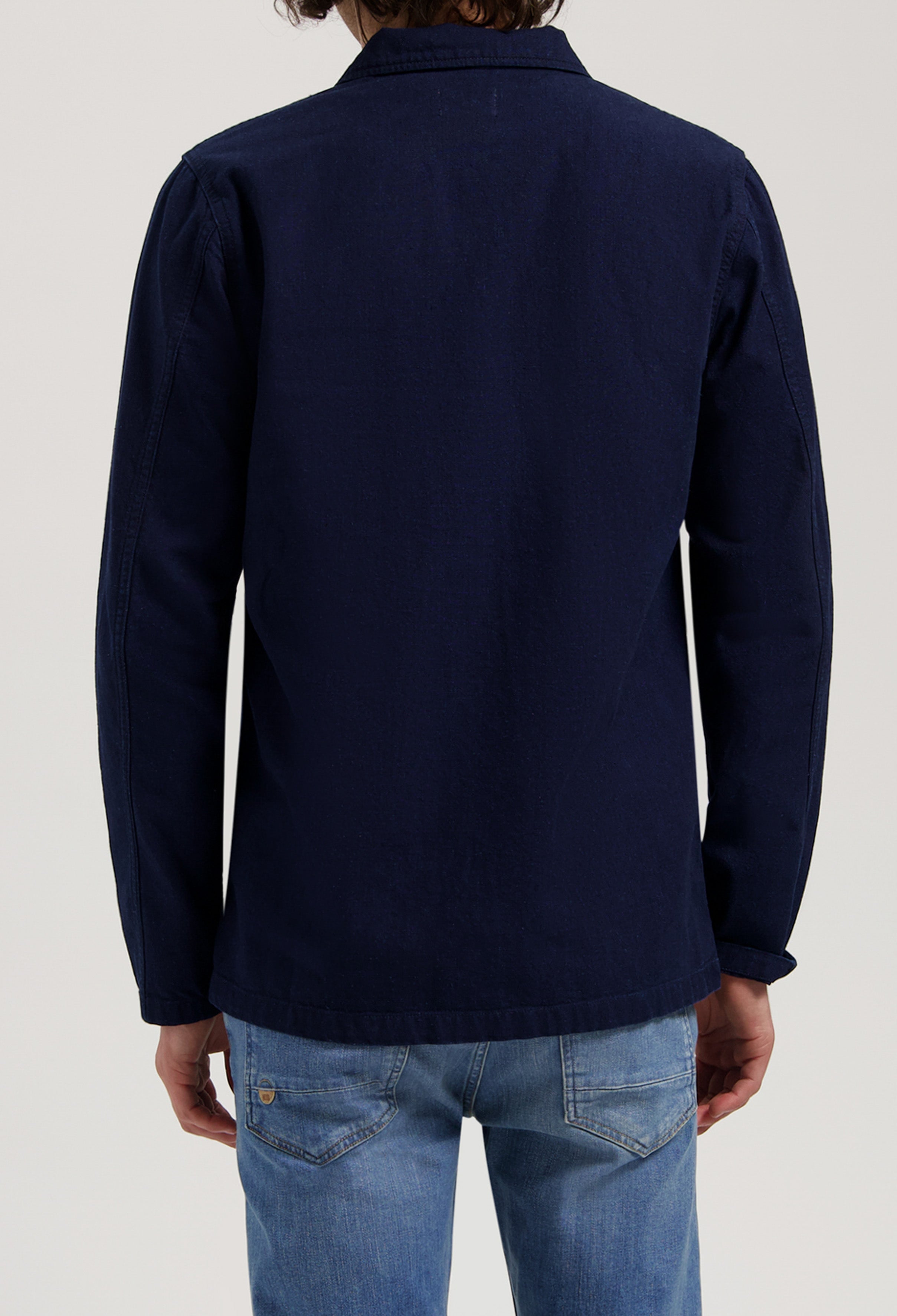 Sustainable MUD Jeans crafted from organic cotton, featuring blue denim in a relaxed fit, styled with a black jacket.