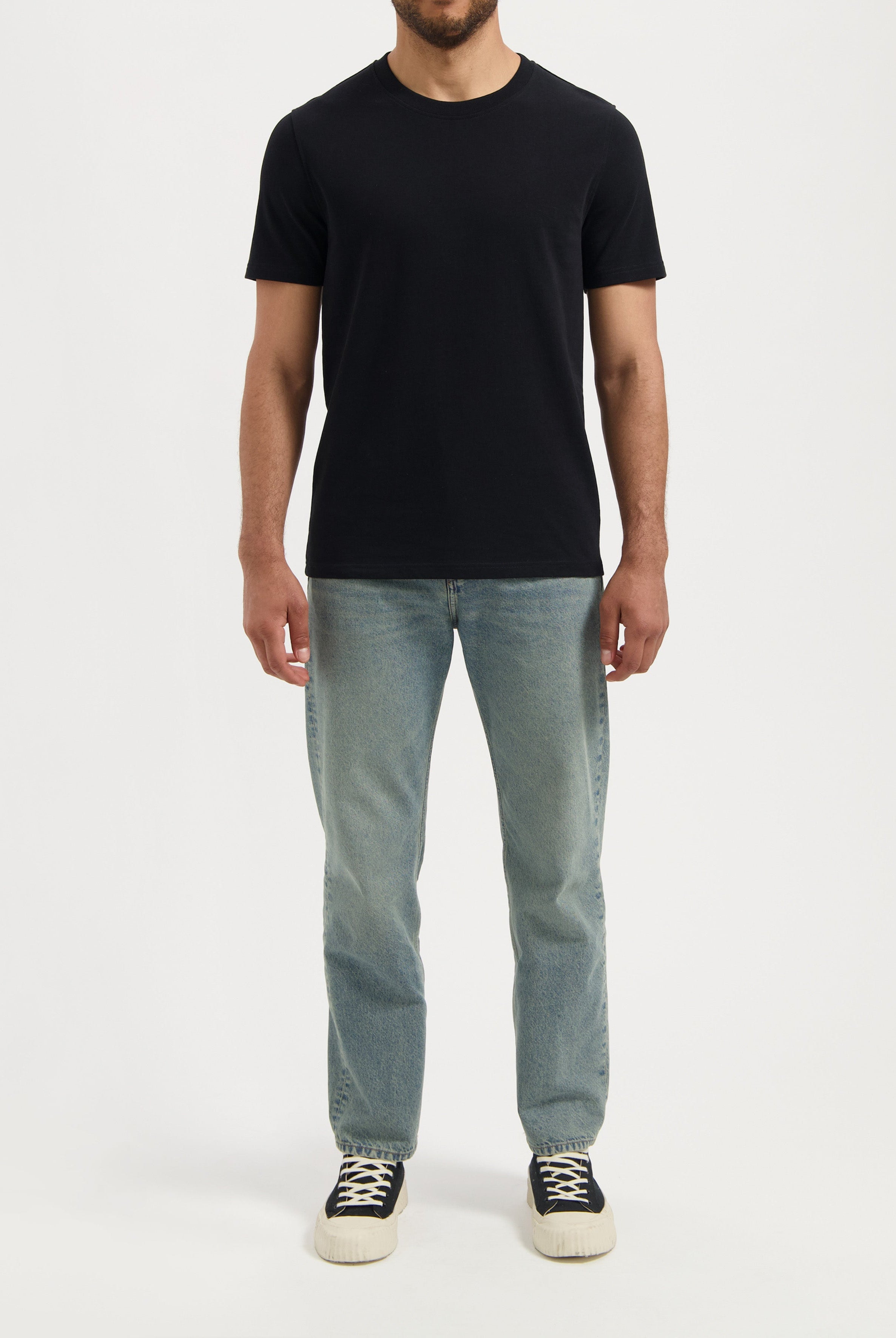 Sustainable MUD Jeans dark blue denim jacket made from organic materials, worn over a white shirt and blue jeans.