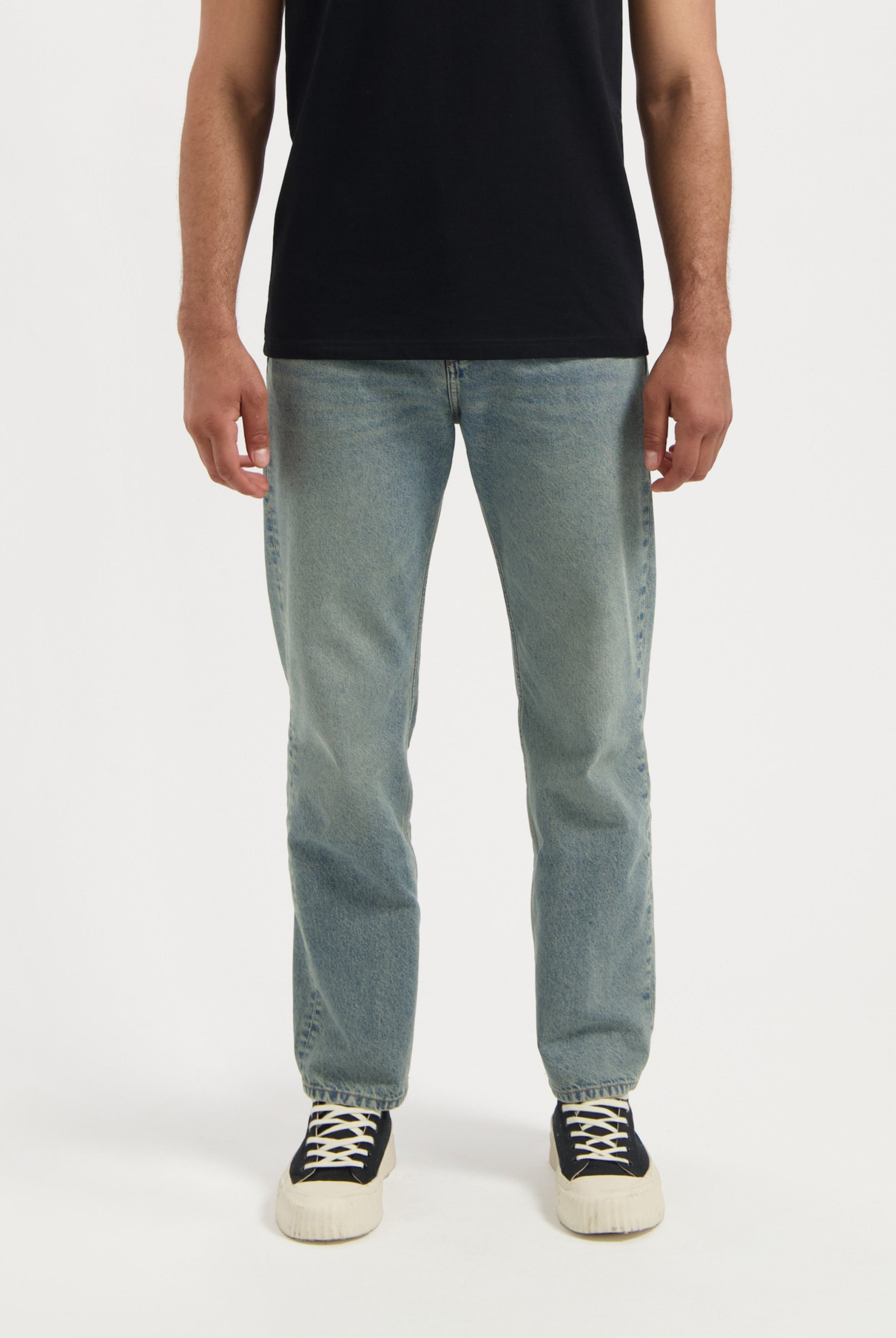 Man wearing sustainable MUD Jeans dark blue denim jacket over a tan shirt, emphasizing ethical fashion choices.