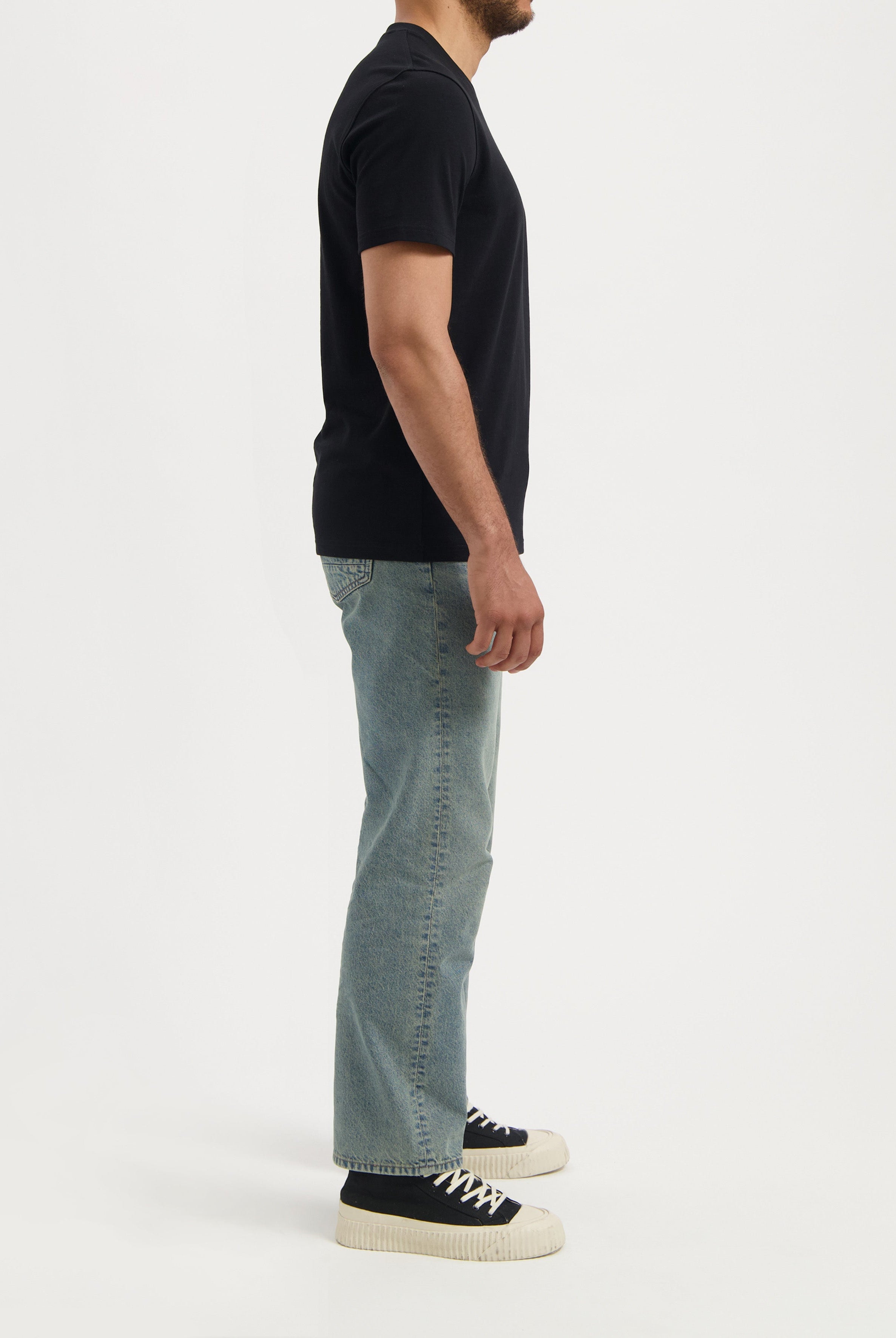 Sustainable MUD Jeans in dark blue denim, styled with a matching jacket and white sneakers, emphasizing ethical fashion.