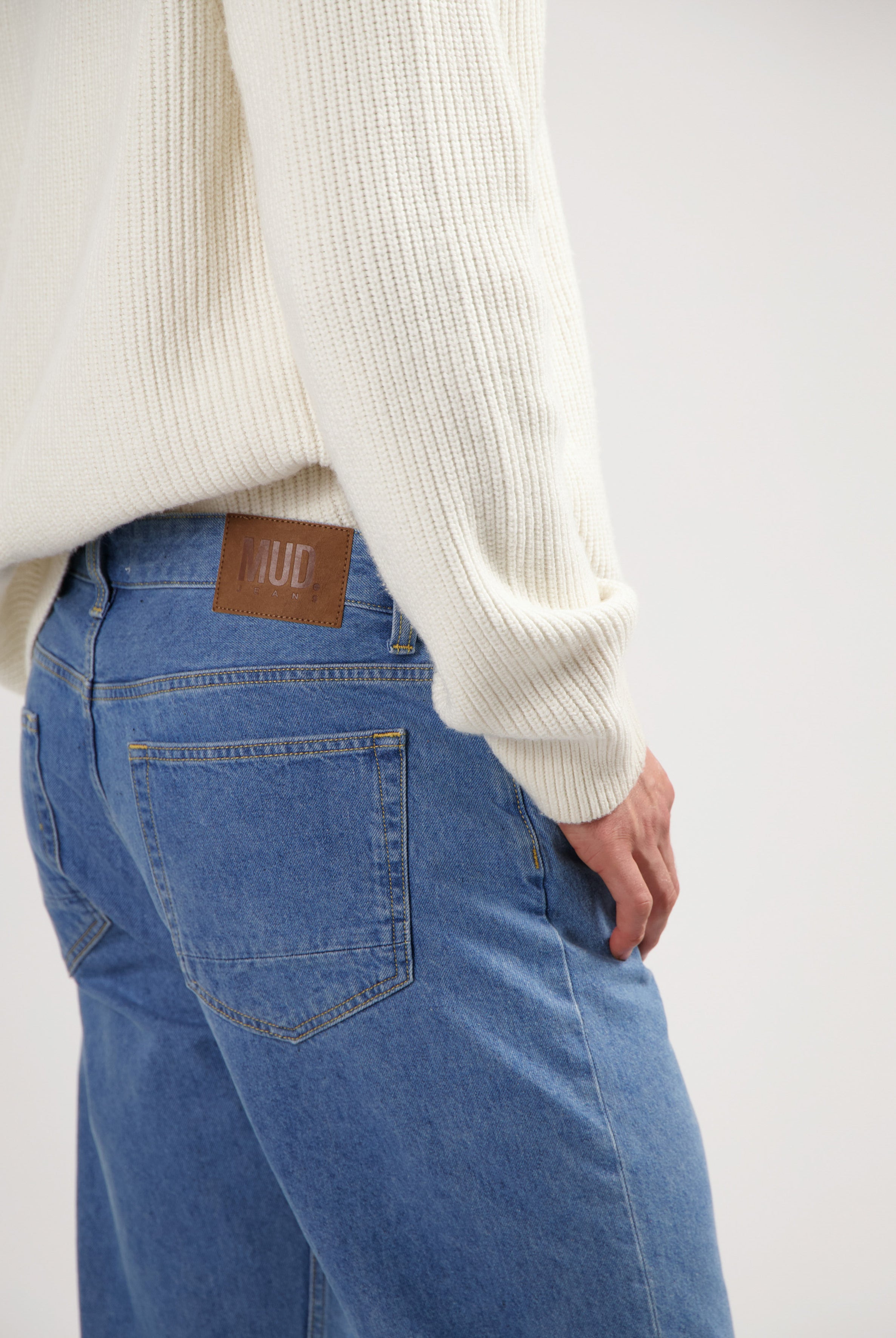 Sustainable MUD Jeans in blue denim, showcasing a comfortable fit and ethical design, paired with a gray top.