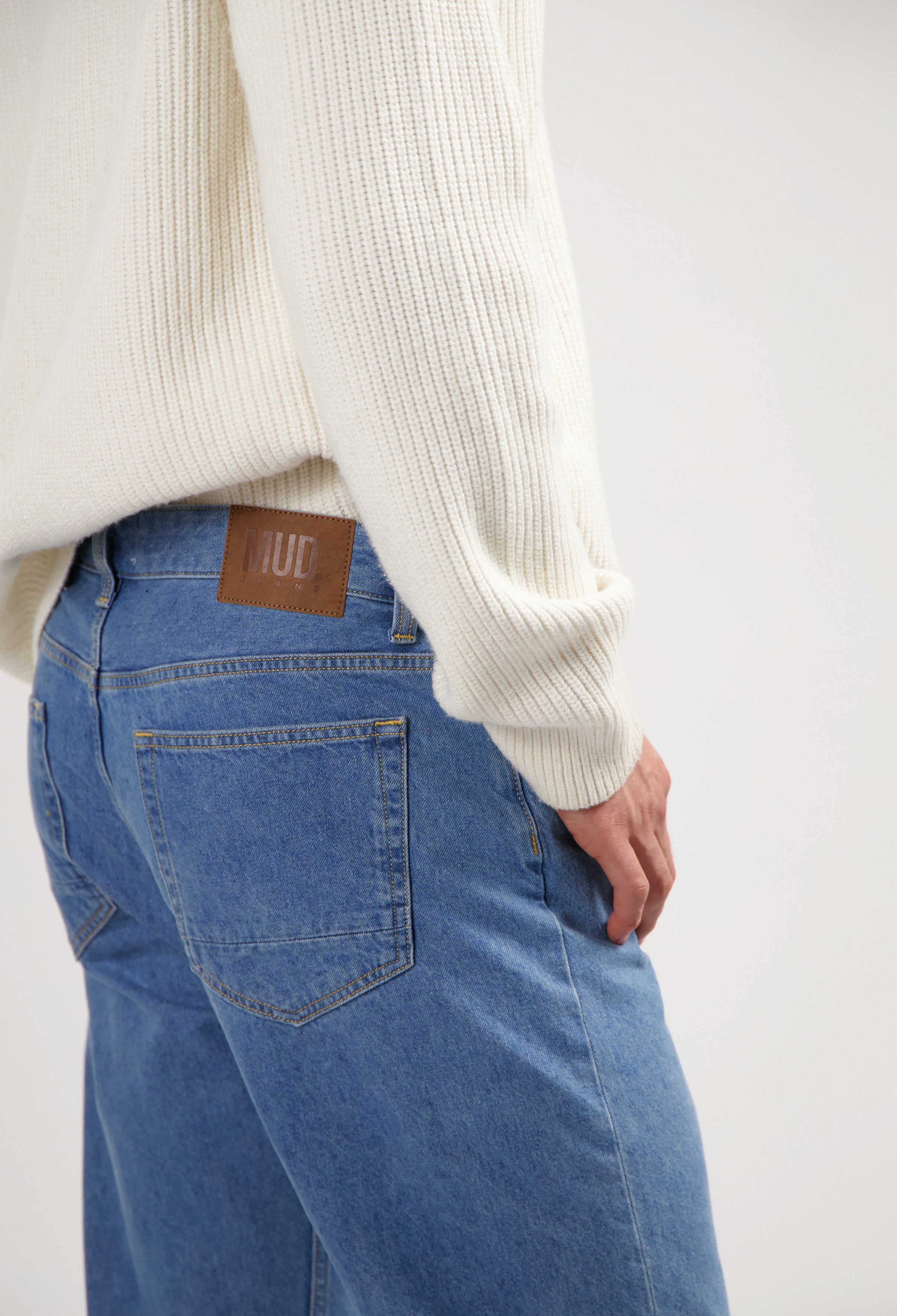 Sustainable MUD Jeans in blue denim, showcasing a comfortable fit and ethical design, paired with a gray top.