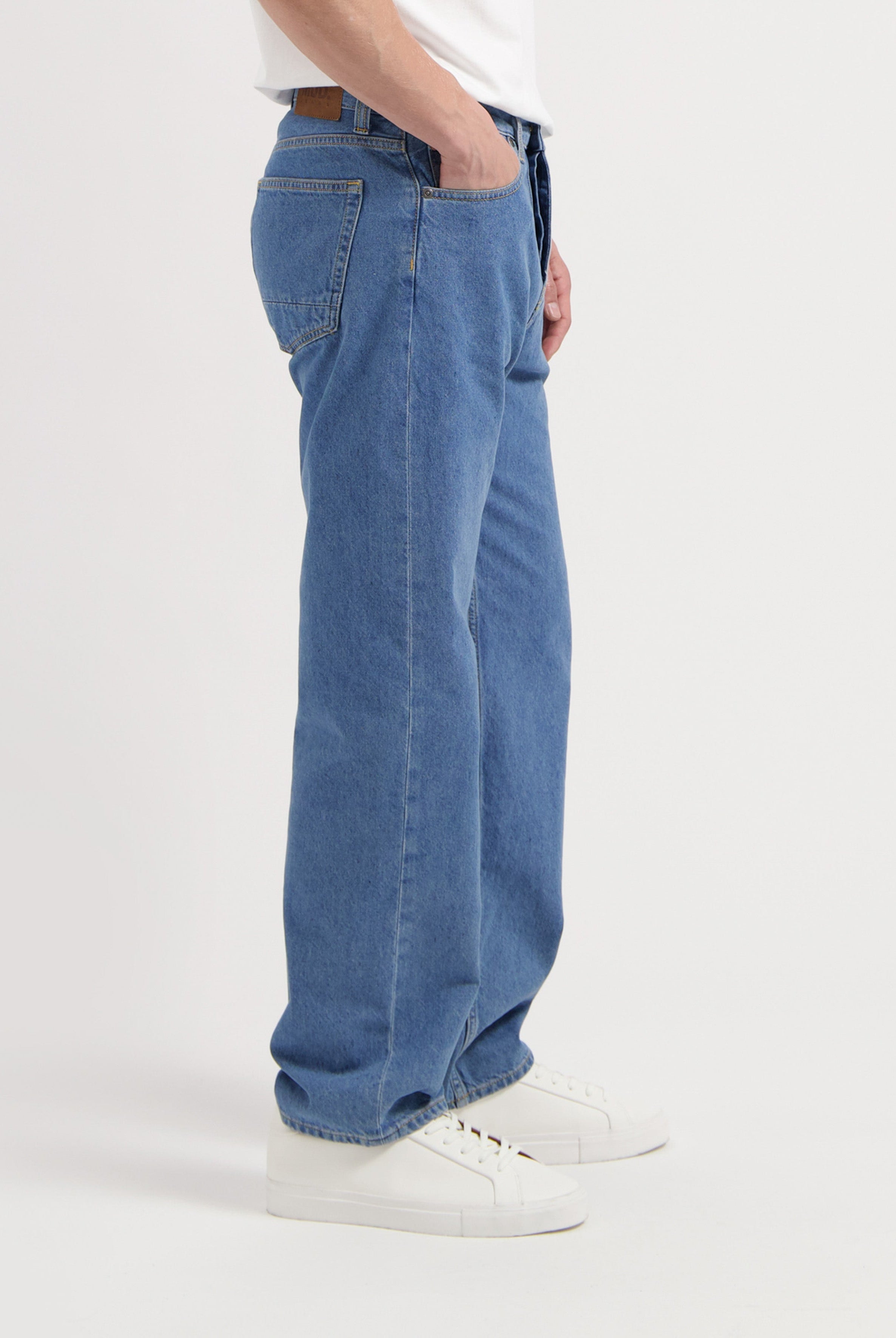 Sustainable MUD Jeans made from organic cotton, featuring classic blue denim, styled with a dark gray long-sleeve shirt.