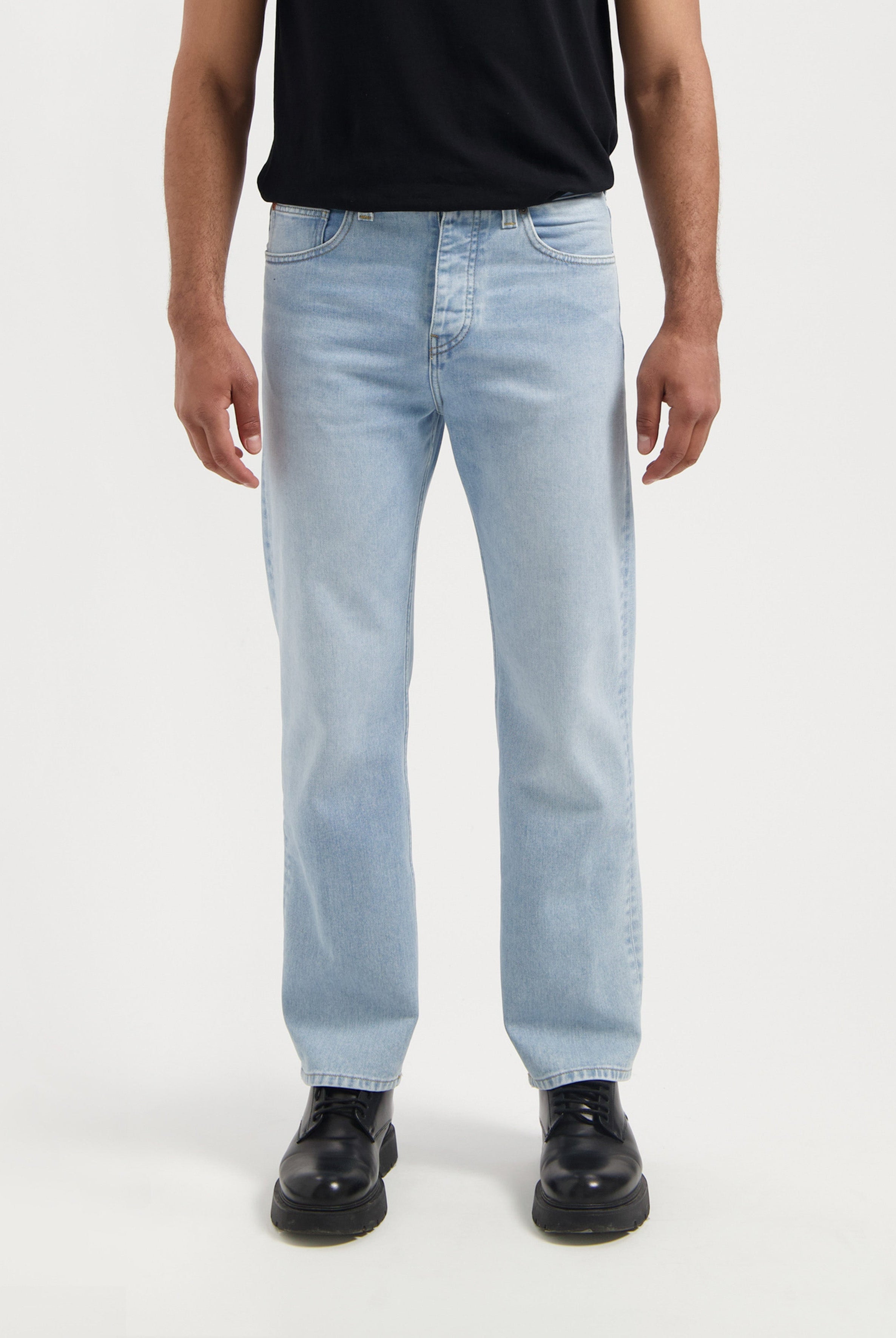 Sustainable MUD Jeans in dark blue denim, featuring a slim fit, crafted from organic cotton and worn with a white shirt.
