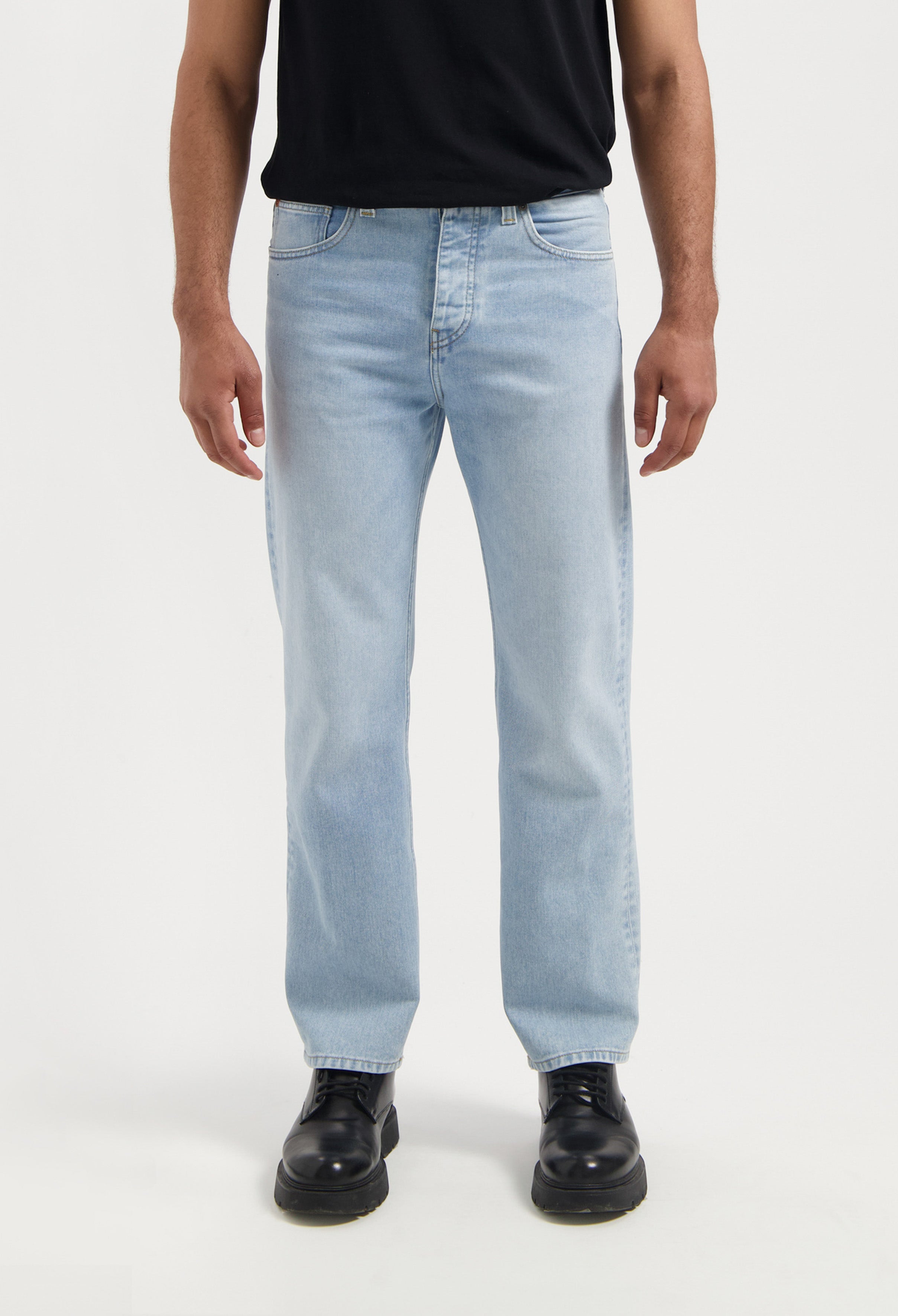 Sustainable MUD Jeans in dark blue denim, featuring a slim fit, crafted from organic cotton and worn with a white shirt.