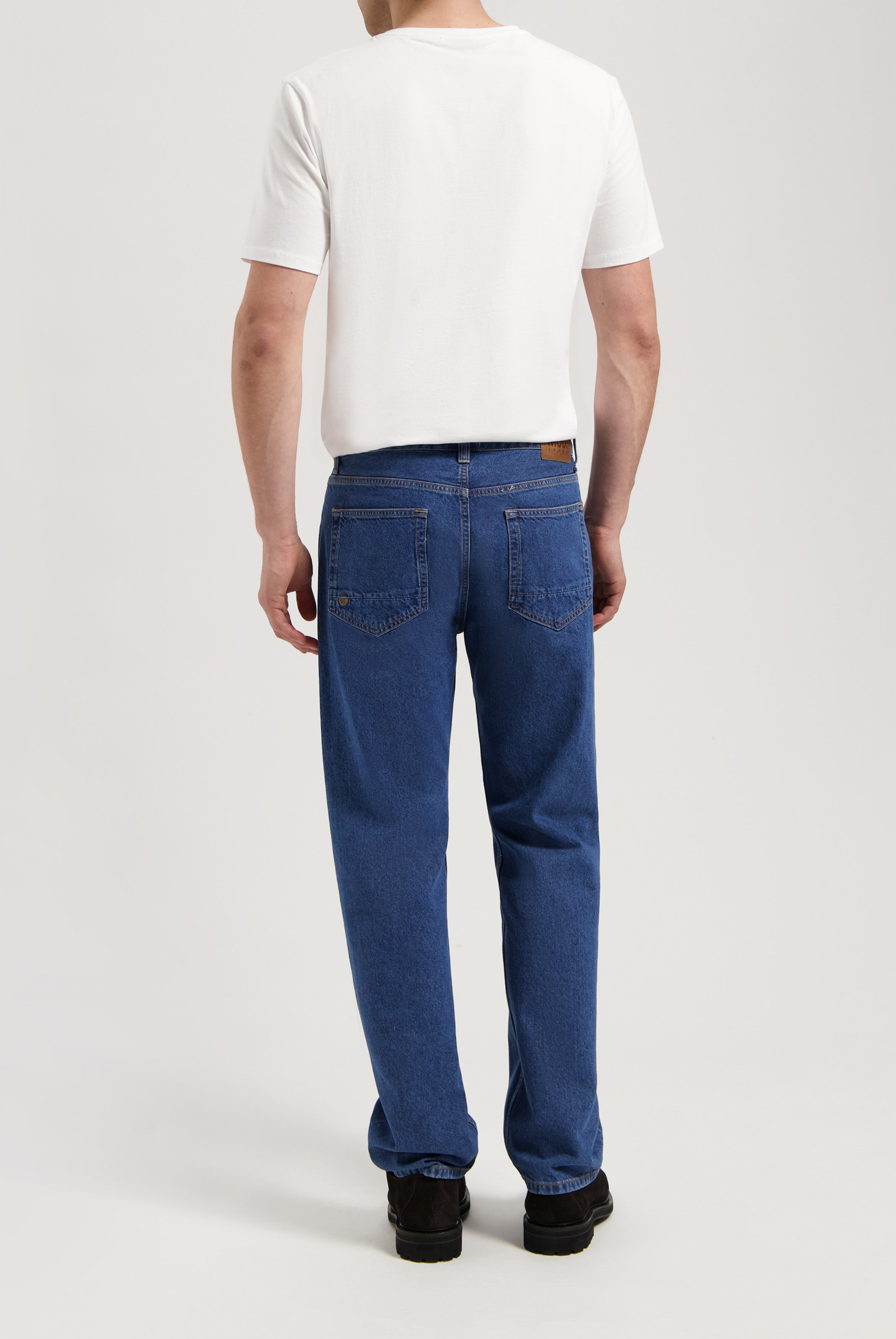 Sustainable MUD Jeans crafted from organic cotton, featuring dark gray denim and a comfortable fit, paired with a white tee.