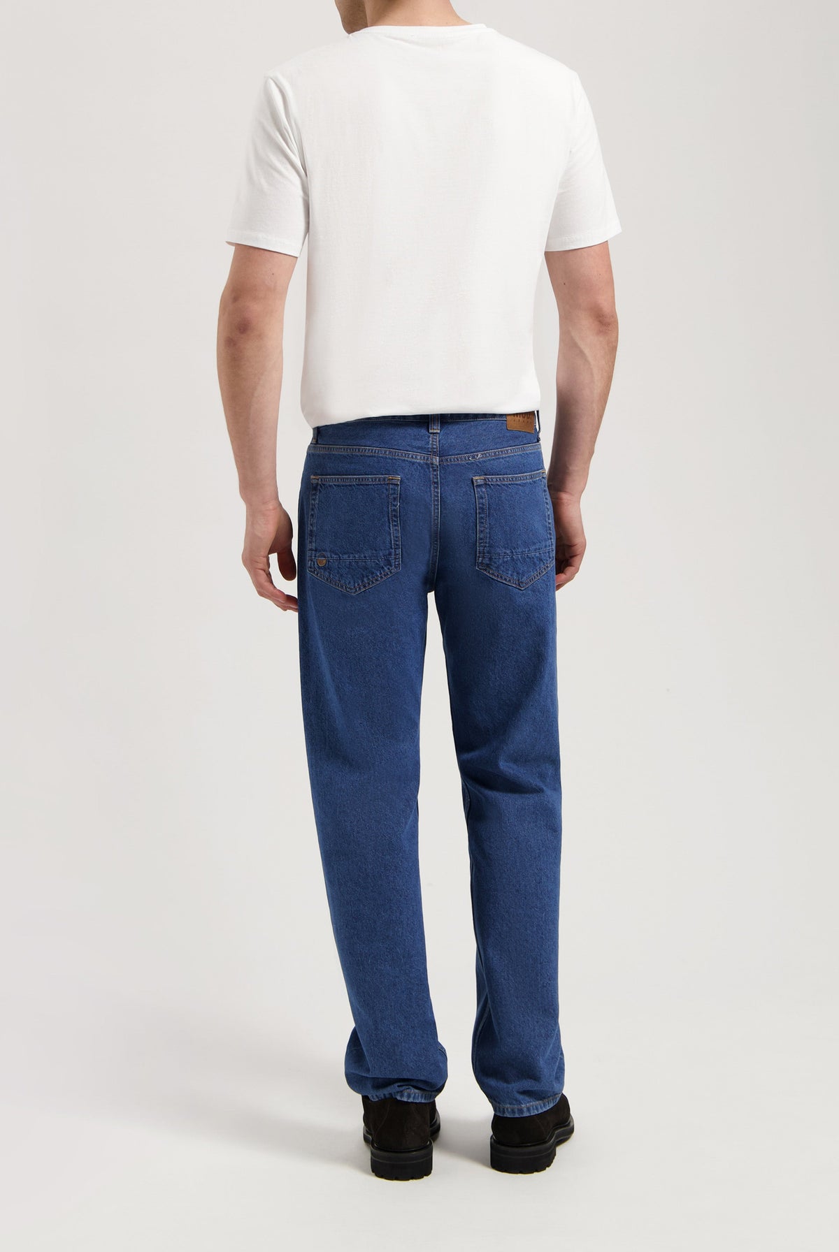 Sustainable MUD Jeans crafted from organic cotton, featuring dark gray denim and a comfortable fit, paired with a white tee.