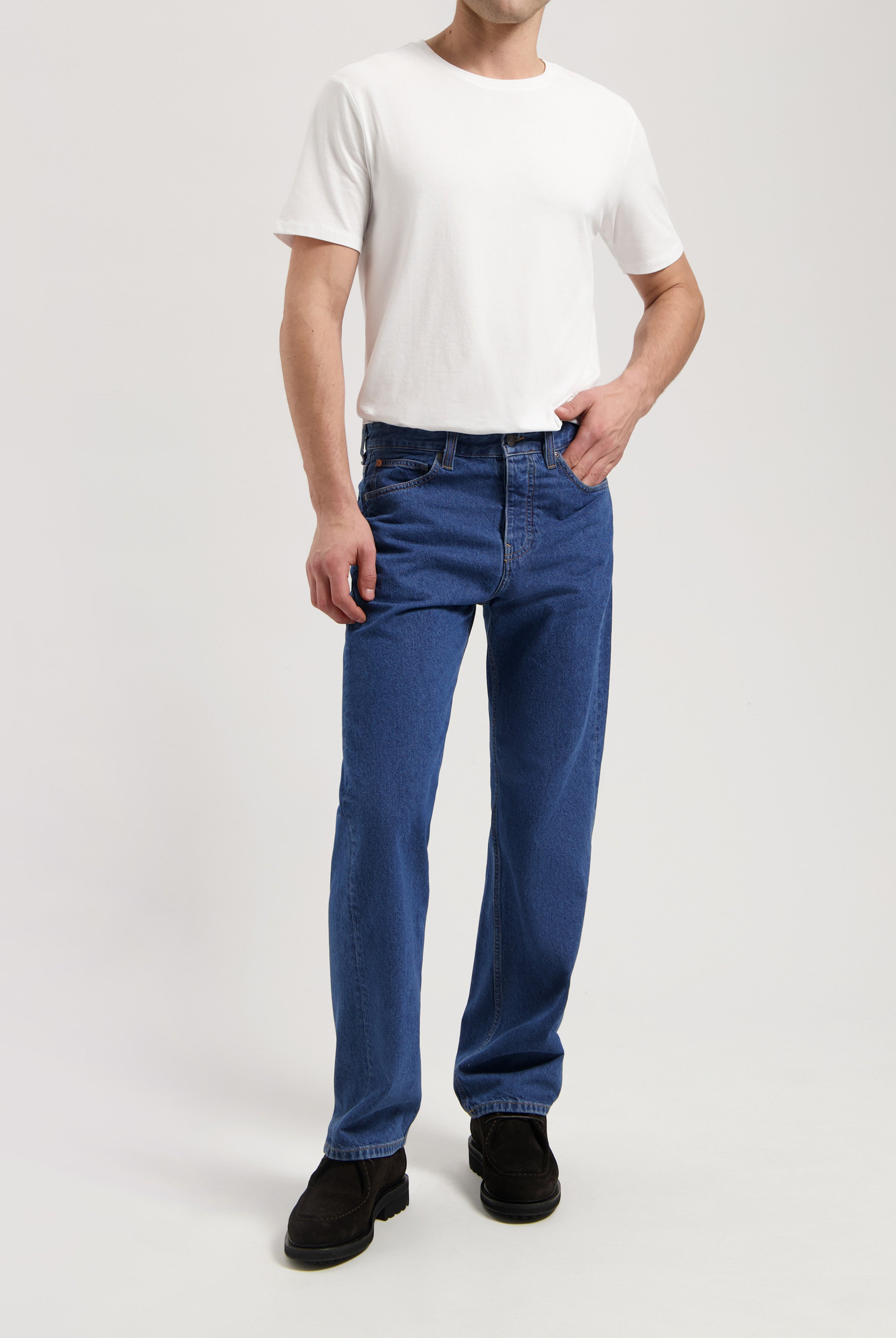 Sustainable MUD Jeans in dark gray denim, slim fit, showcasing ethical fashion paired with black leather shoes.