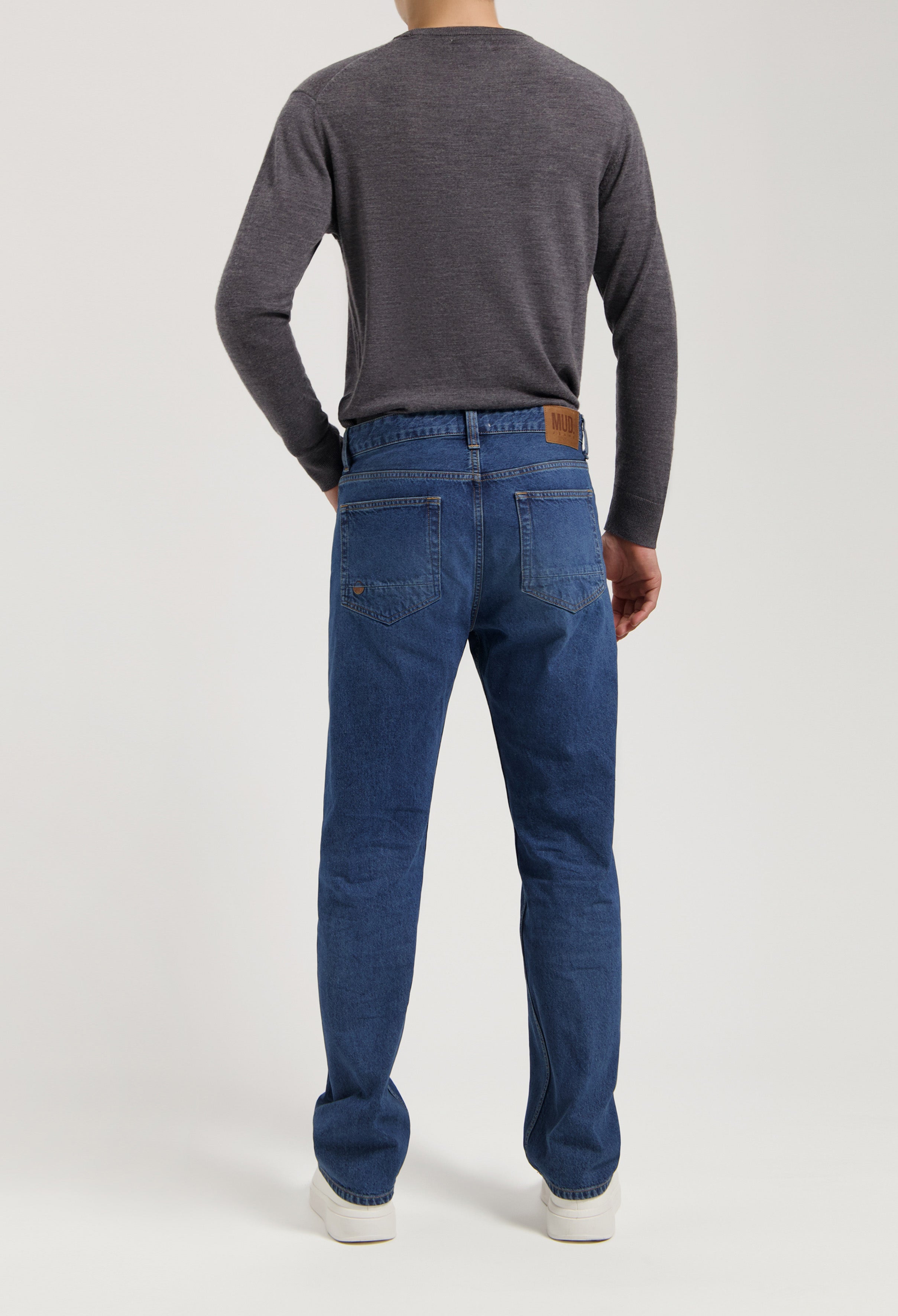 Sustainable MUD Jeans in classic blue denim, crafted from ethical materials, paired with a dark gray sweater.
