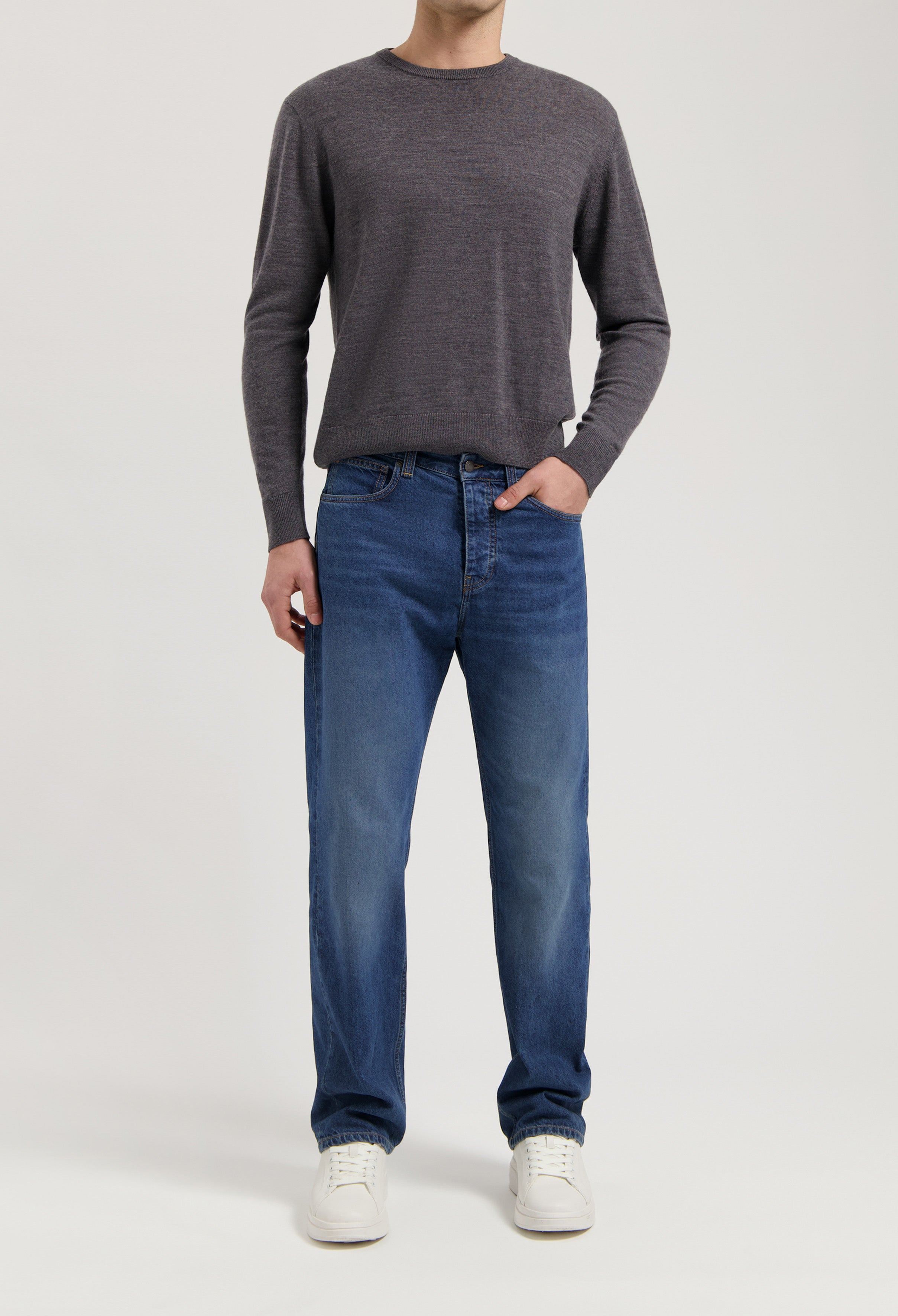 Sustainable MUD Jeans in classic blue, crafted from organic cotton, paired with a gray sweater for an ethical fashion look.