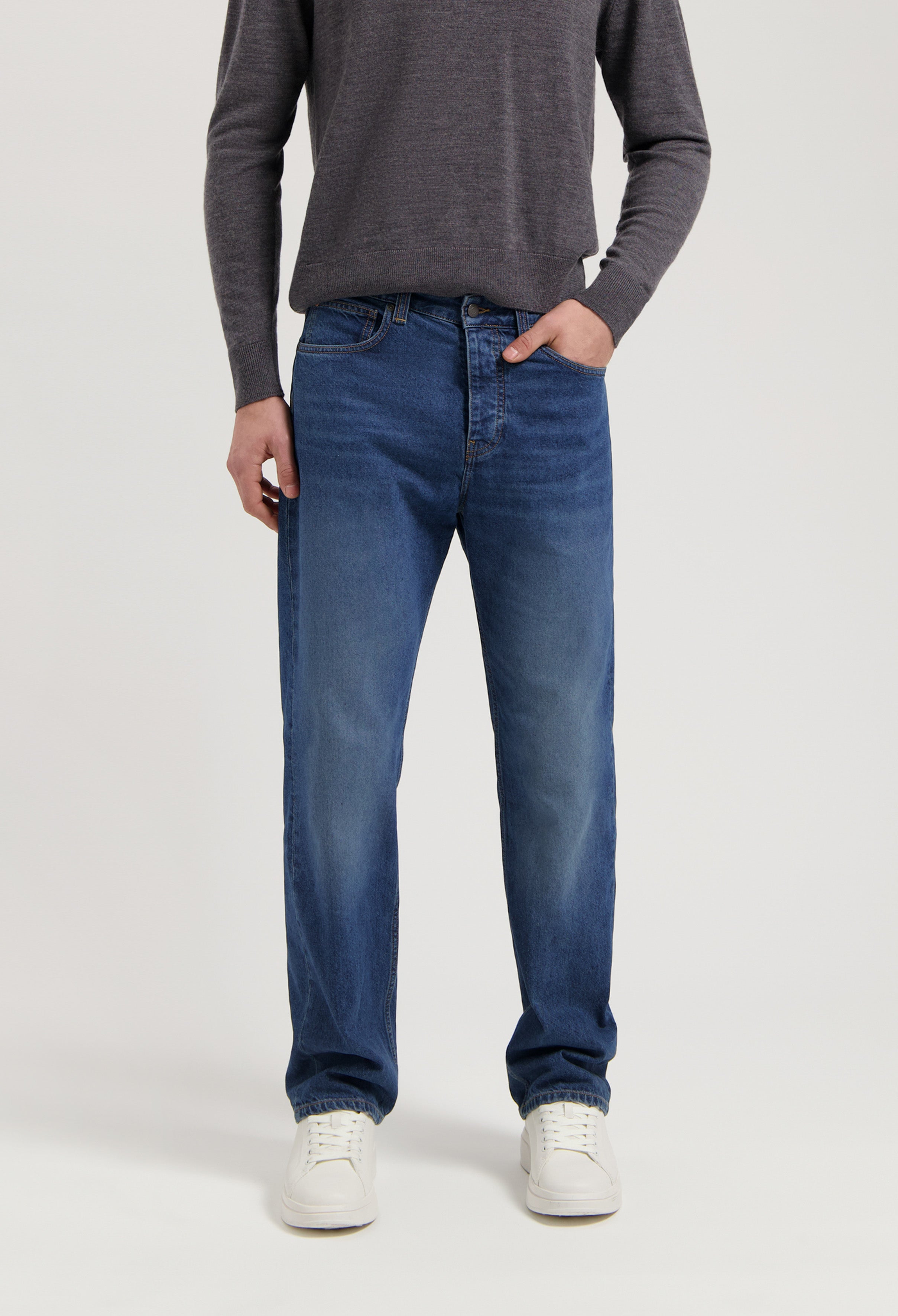 Sustainable MUD Jeans made from eco-friendly materials, featuring classic blue denim in a straight fit, paired with a gray sweater.