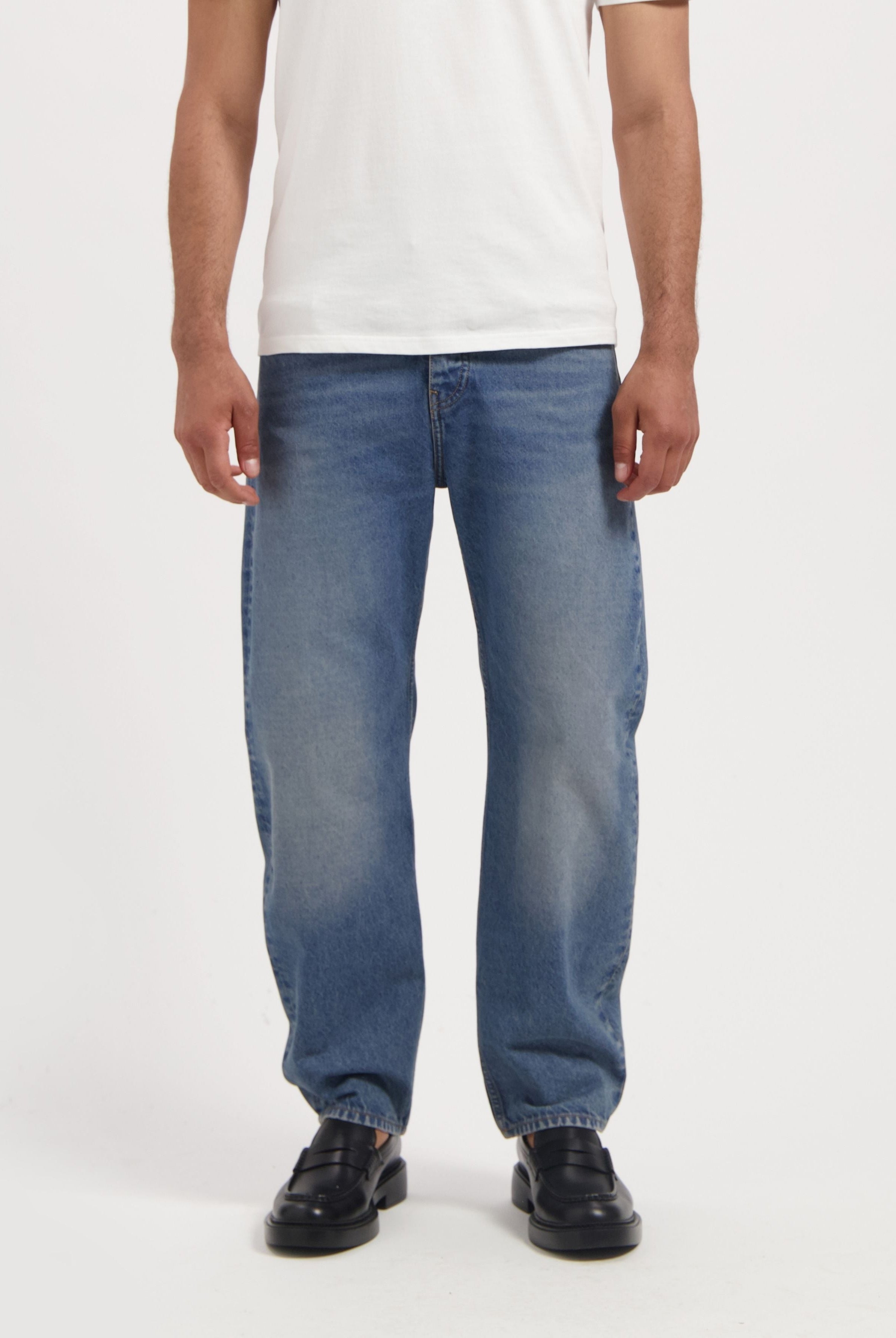 Sustainable MUD Jeans crafted from organic cotton in a light blue shade, paired with a black t-shirt, highlighting ethical fashion.