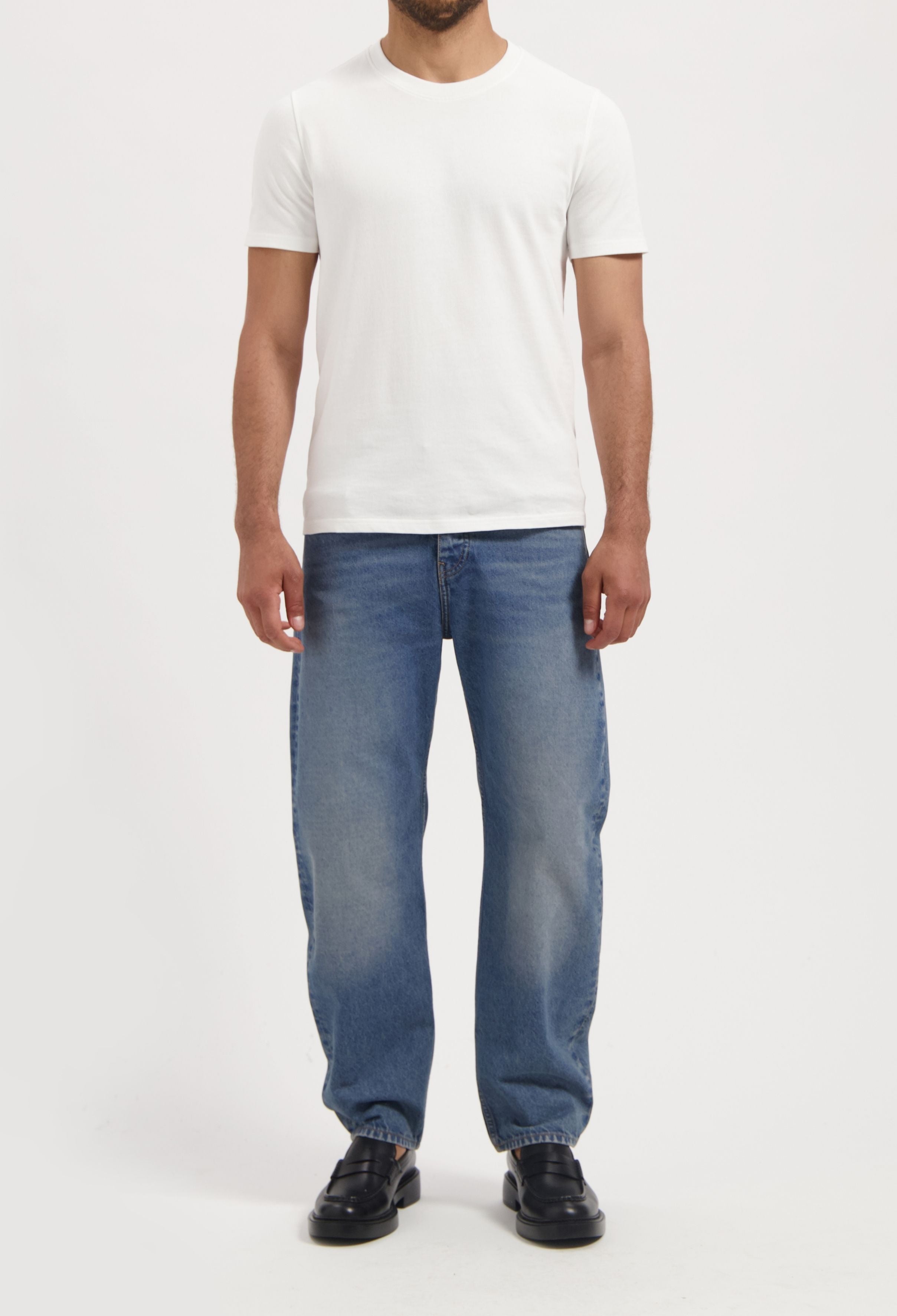 Sustainable MUD Jeans in light blue, crafted from ethical organic cotton, paired with white sneakers for a casual style.
