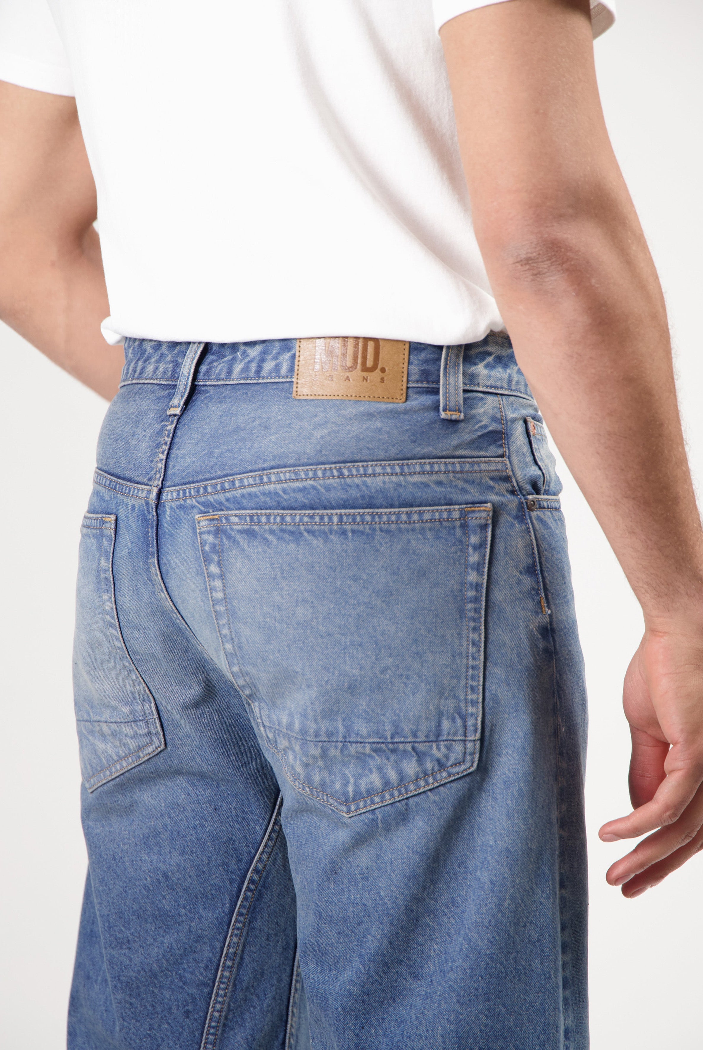 Sustainable MUD Jeans in light blue denim, ethical fashion, paired with black tee and black shoes for a classic look.