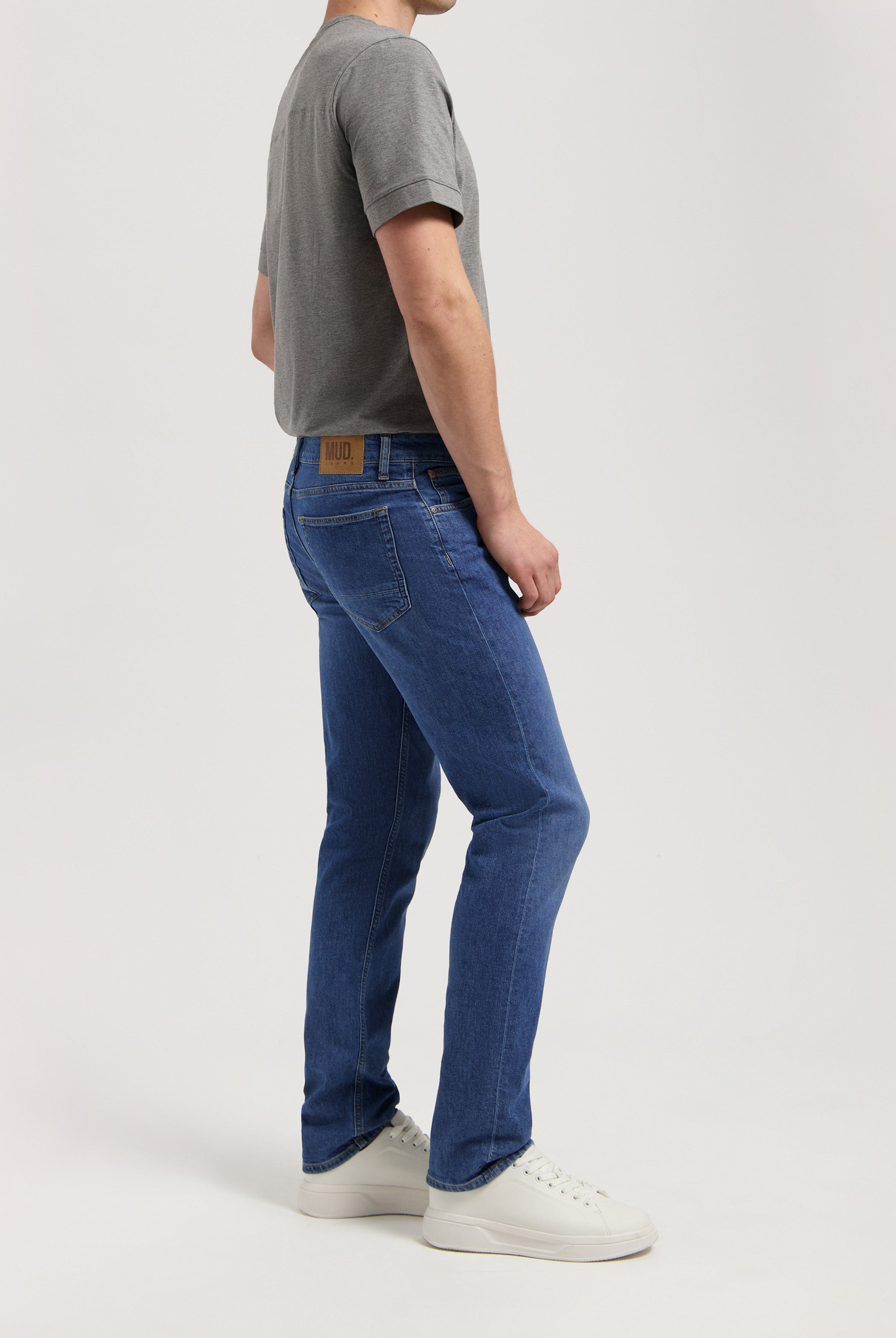 Sustainable MUD Jeans in dark blue denim, tailored fit, made from organic materials, paired with a white t-shirt.