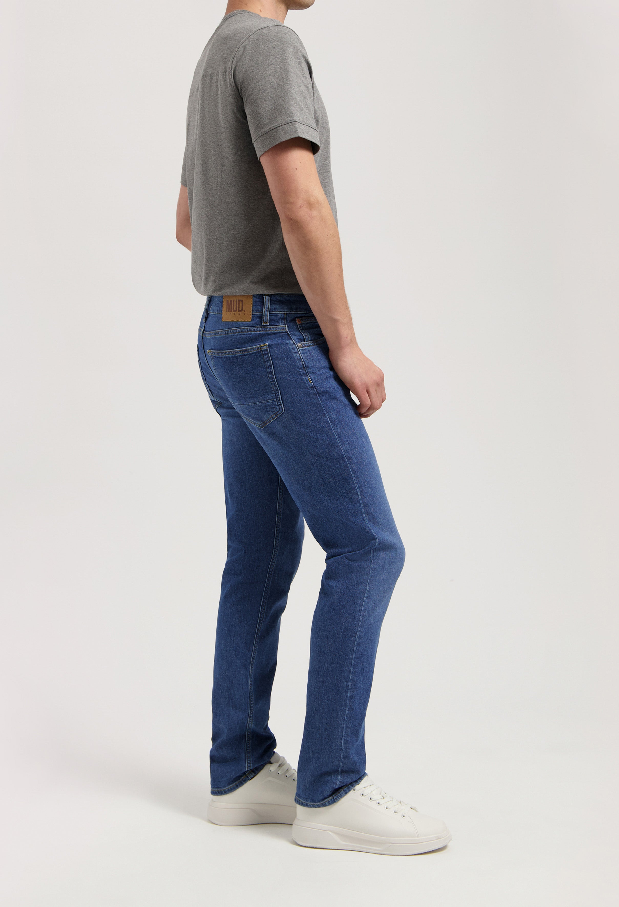 Sustainable MUD Jeans in dark blue denim, tailored fit, made from organic materials, paired with a white t-shirt.
