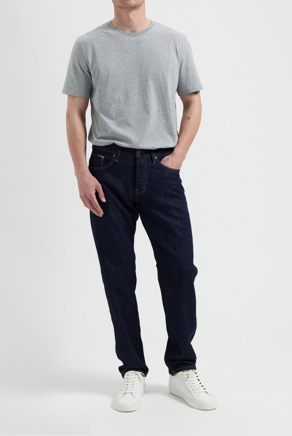 Sustainable MUD Jeans in blue denim, classic fit, paired with a gray t-shirt featuring eco-friendly messaging.