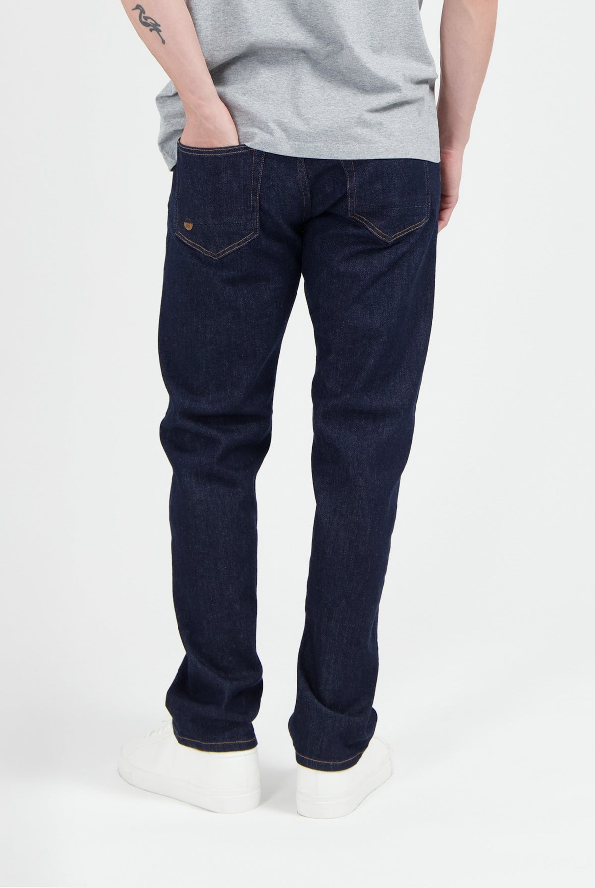 Sustainable MUD Jeans in dark blue denim, classic fit, made from ethical cotton, paired with white sneakers.