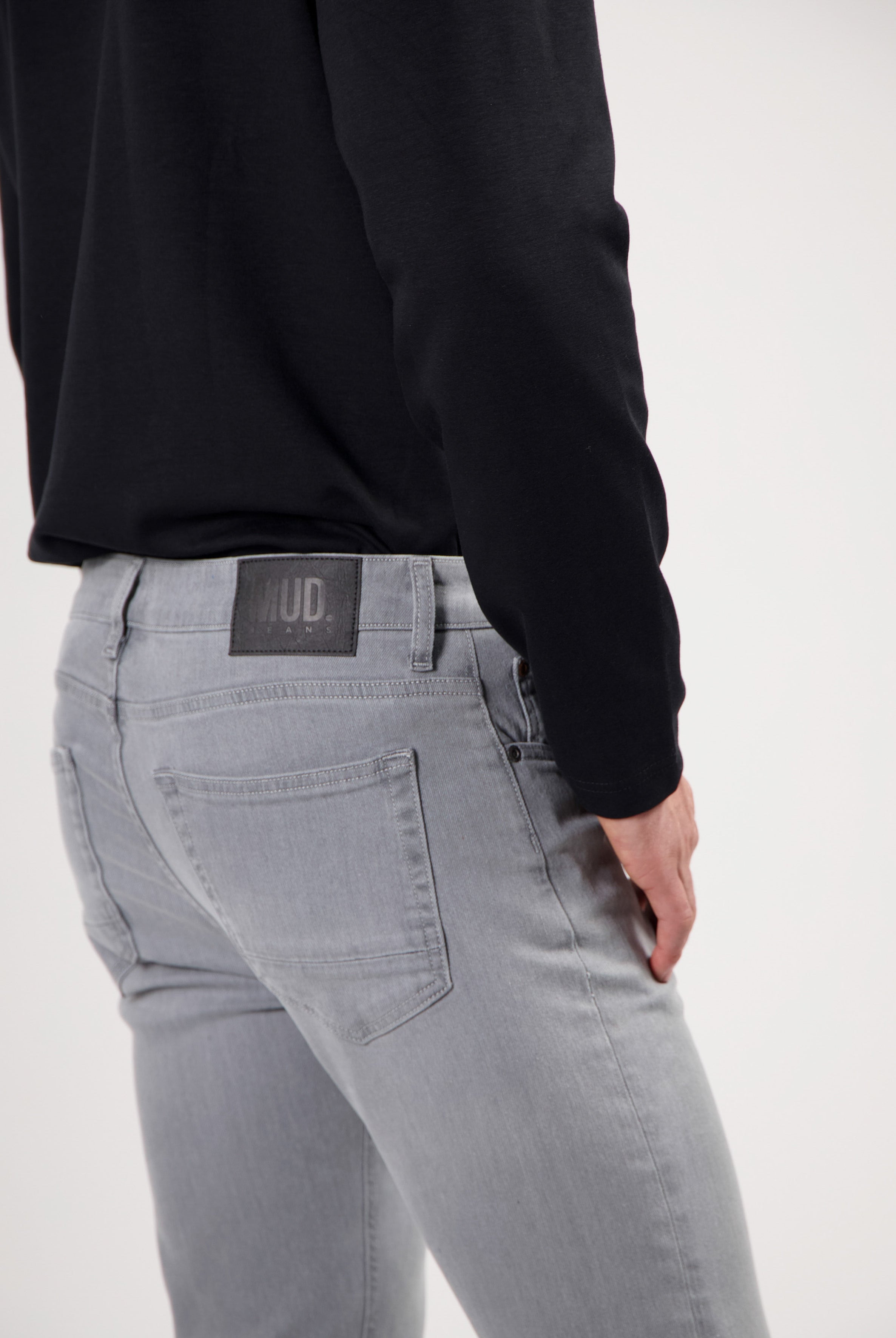 Sustainable MUD Jeans made from organic cotton, classic blue denim, paired with a gray sweater and beige sneakers.