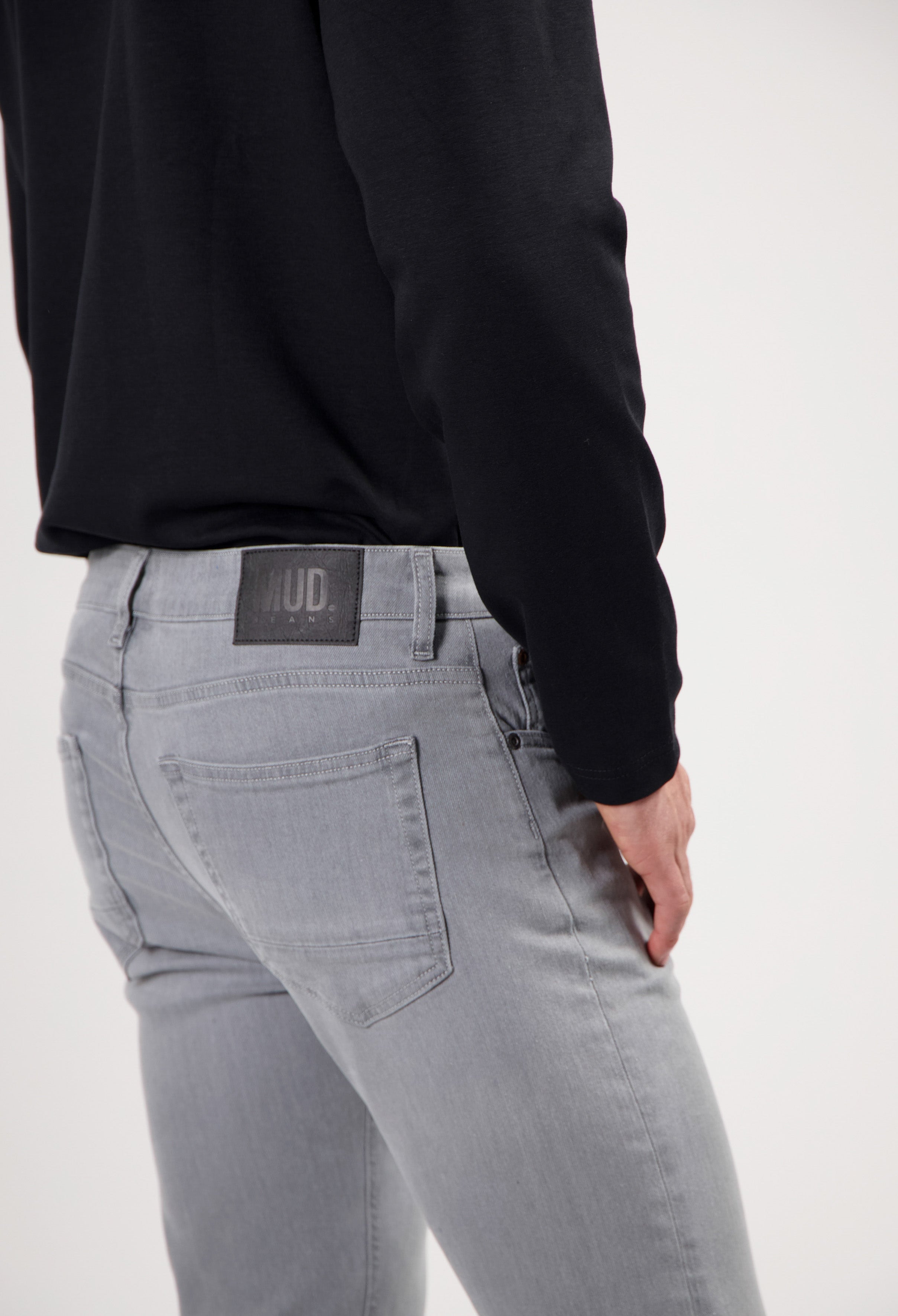 Sustainable MUD Jeans made from organic cotton, classic blue denim, paired with a gray sweater and beige sneakers.