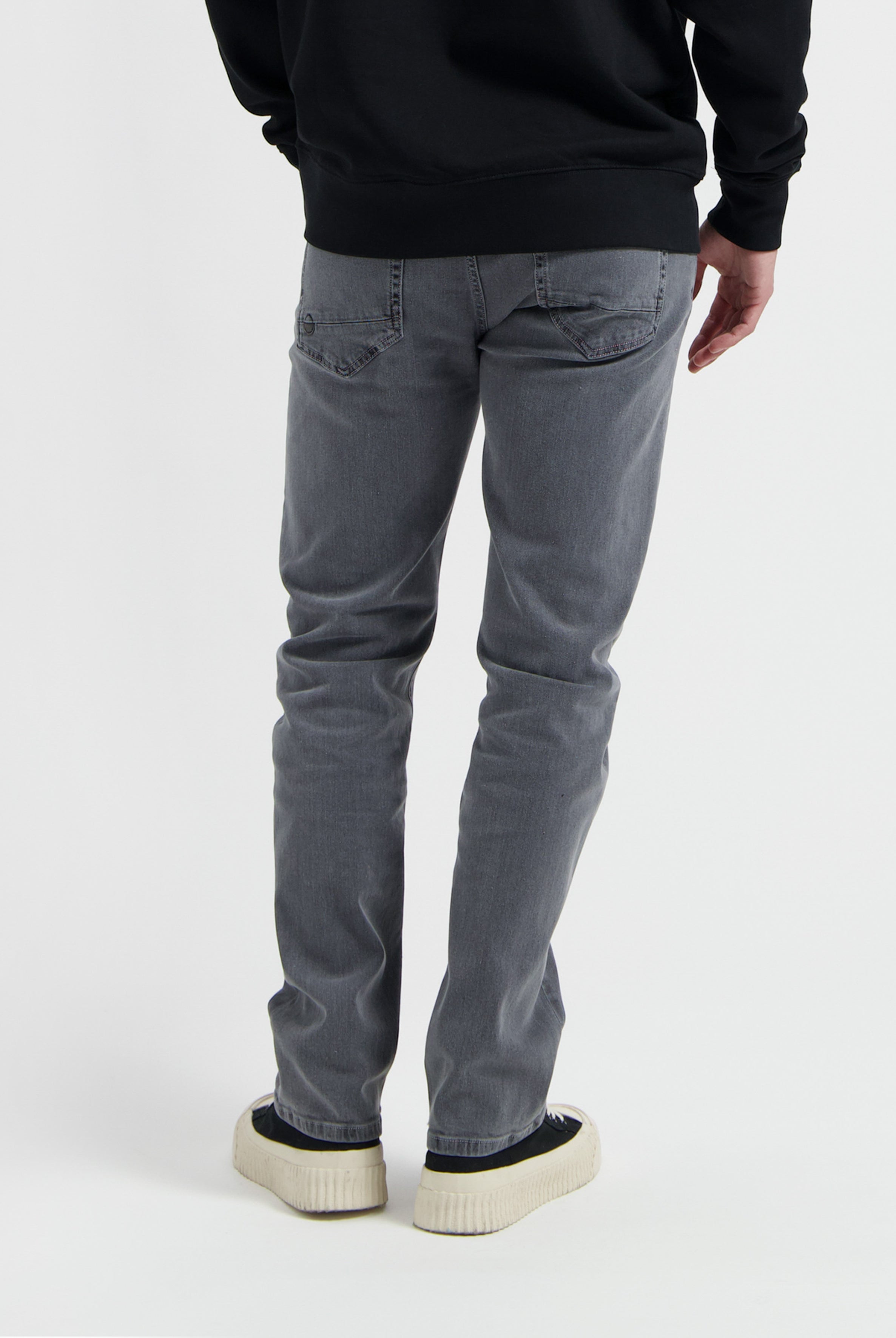 Sustainable MUD Jeans made from organic cotton, featuring deep blue denim in a slim fit, paired with a gray sweater.