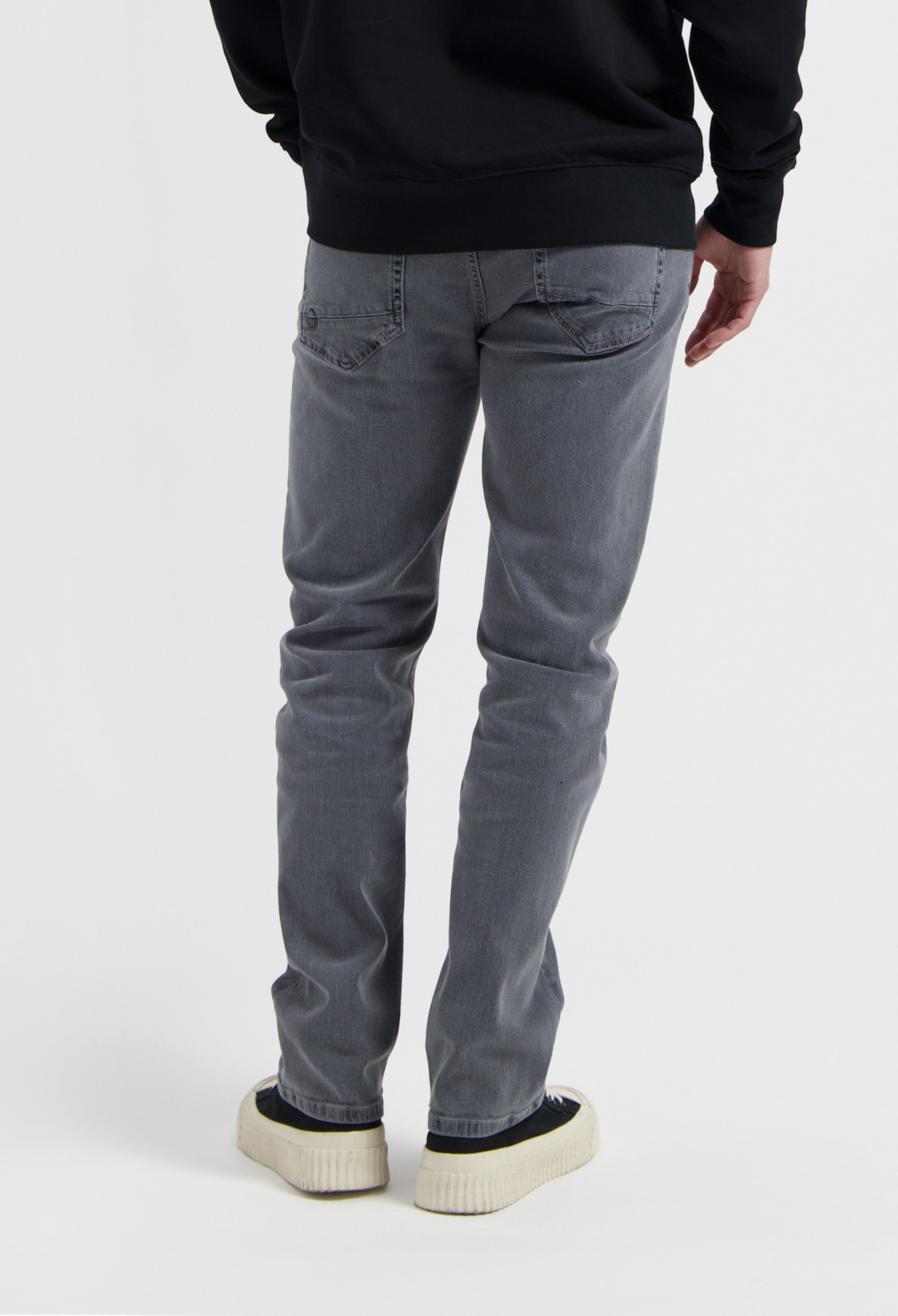 Sustainable MUD Jeans made from organic cotton, featuring deep blue denim in a slim fit, paired with a gray sweater.