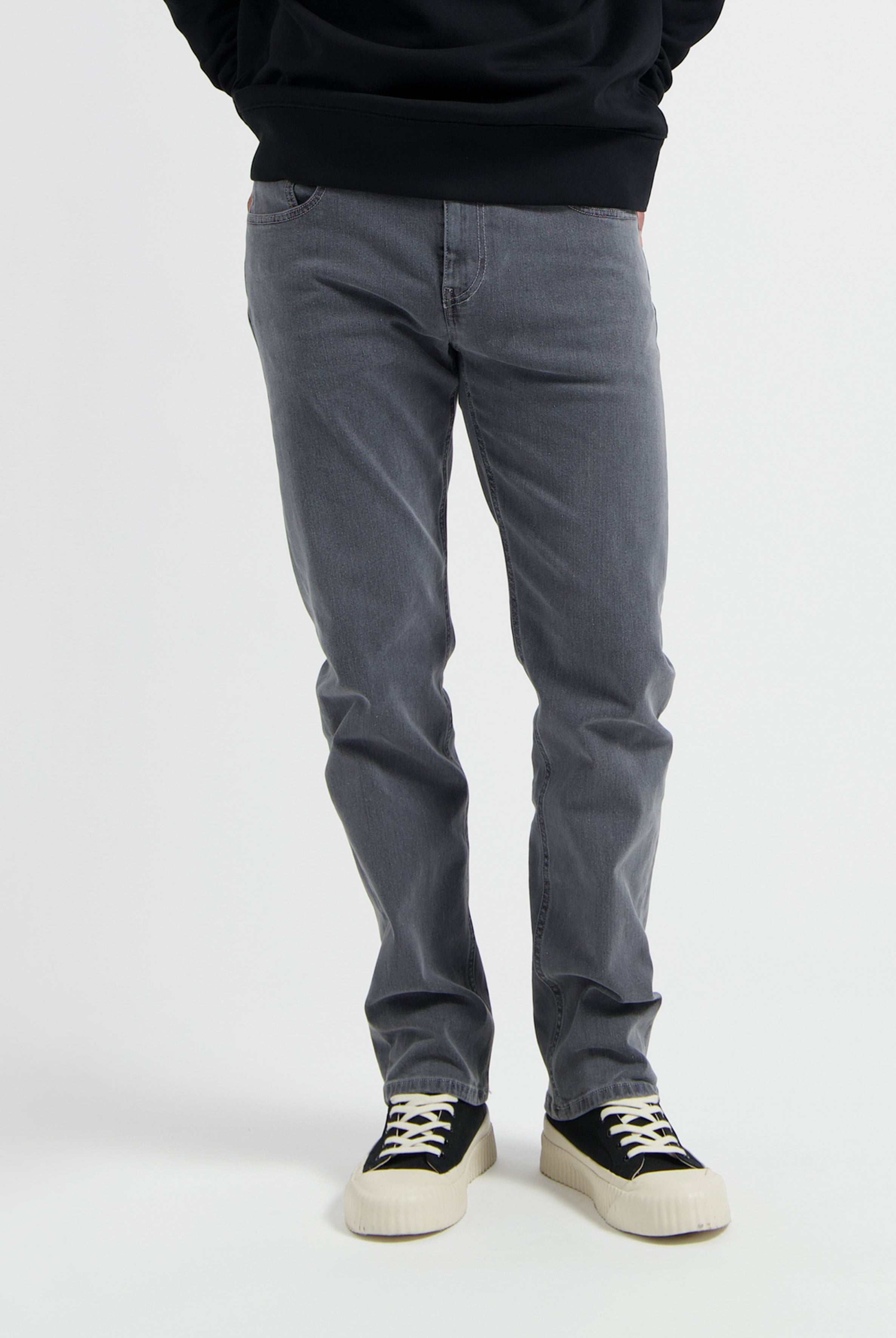 Sustainable MUD Jeans in light blue denim with ethical craftsmanship, paired with a soft gray sweater for casual style.