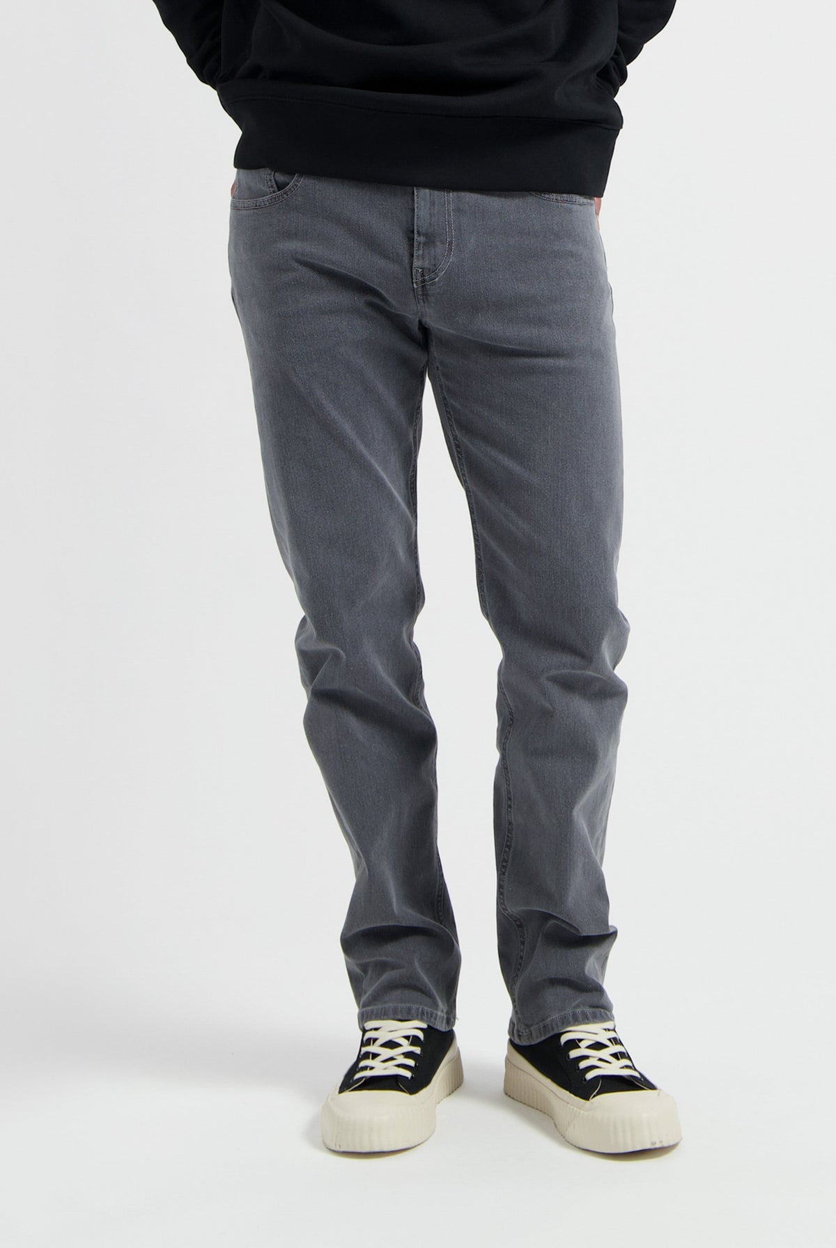Sustainable MUD Jeans in light blue denim with ethical craftsmanship, paired with a soft gray sweater for casual style.