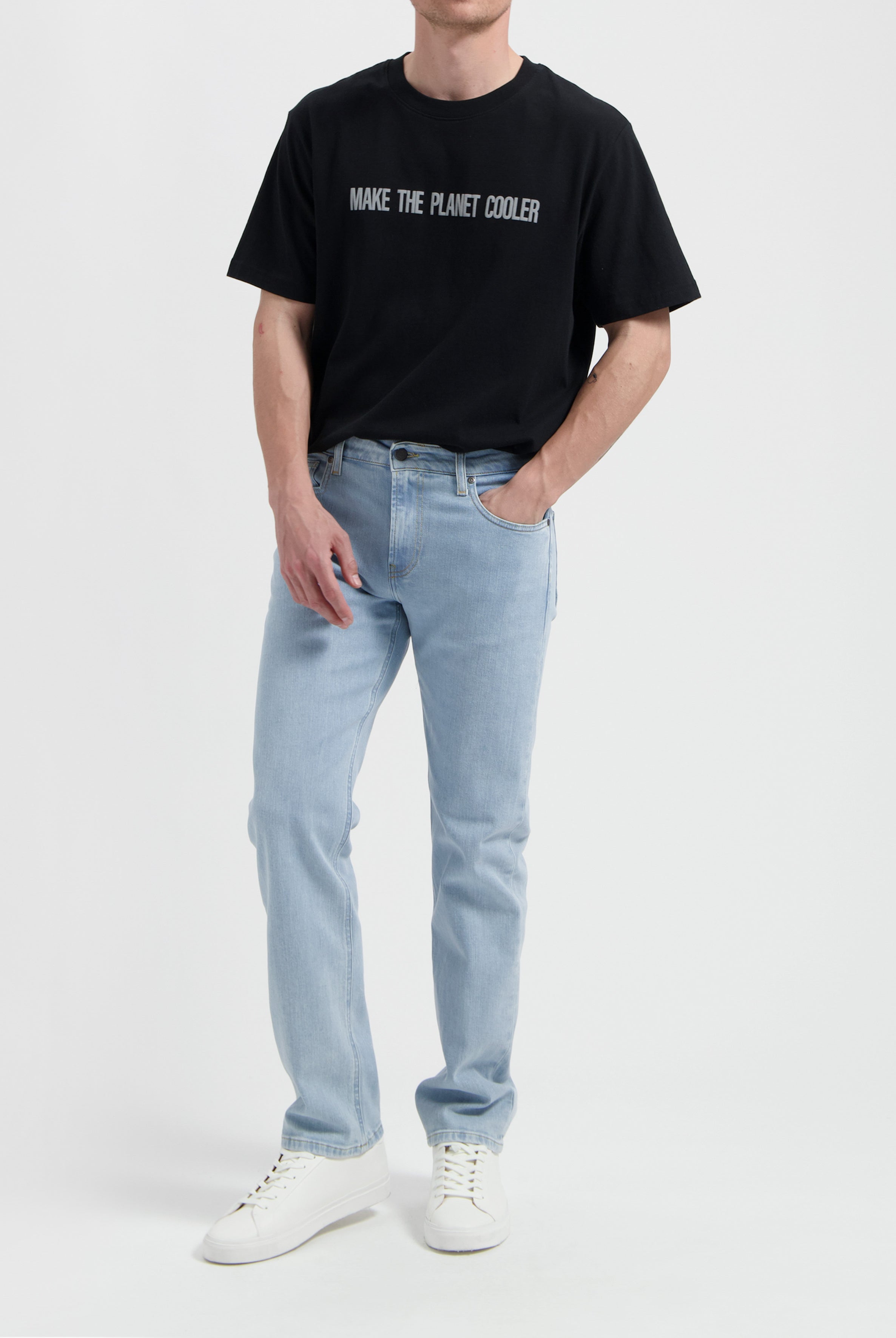 Sustainable MUD Jeans in light blue denim, featuring a classic fit, ethically made, worn with a white tee and sneakers.