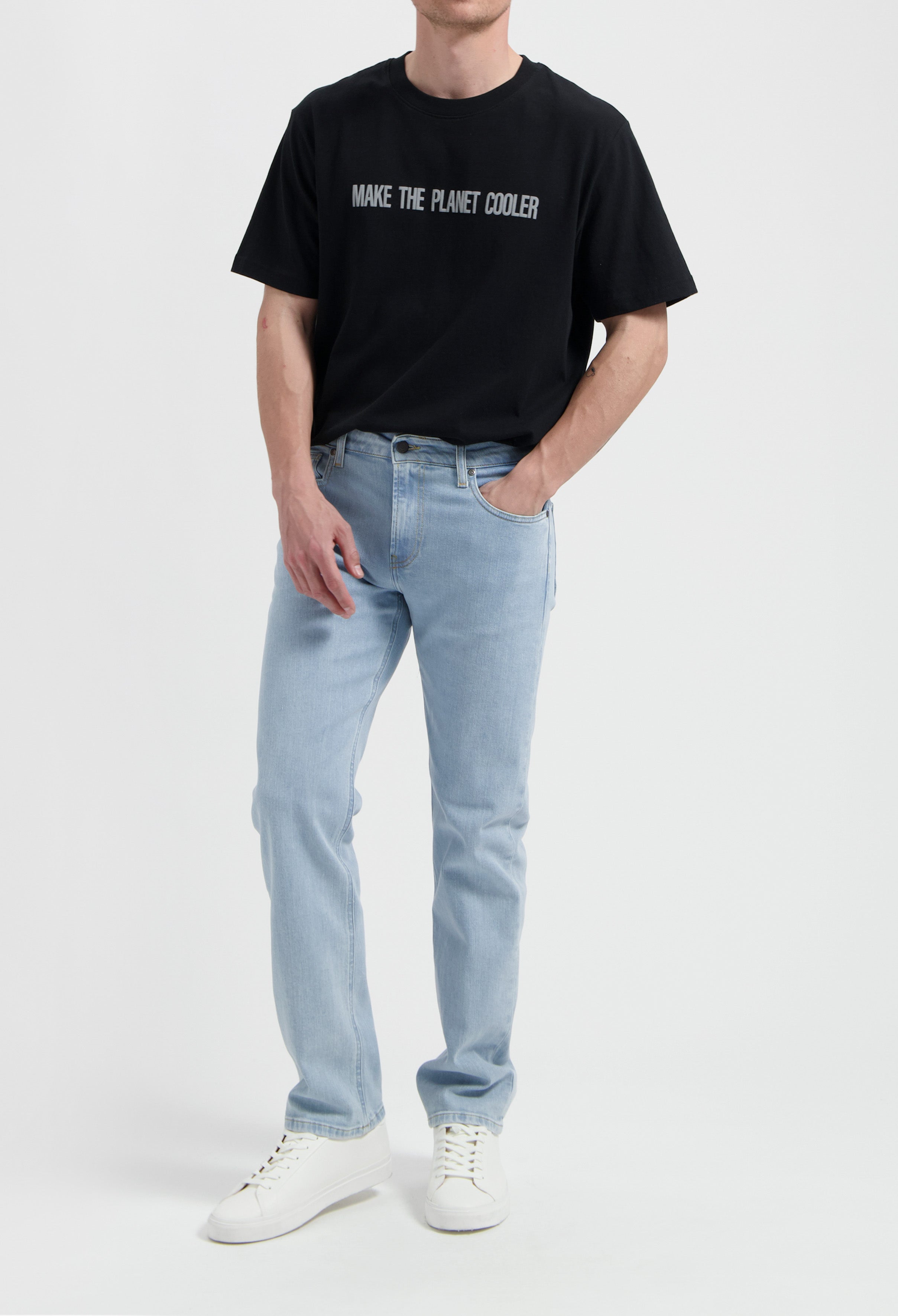 Sustainable MUD Jeans in light blue denim, featuring a classic fit, ethically made, worn with a white tee and sneakers.