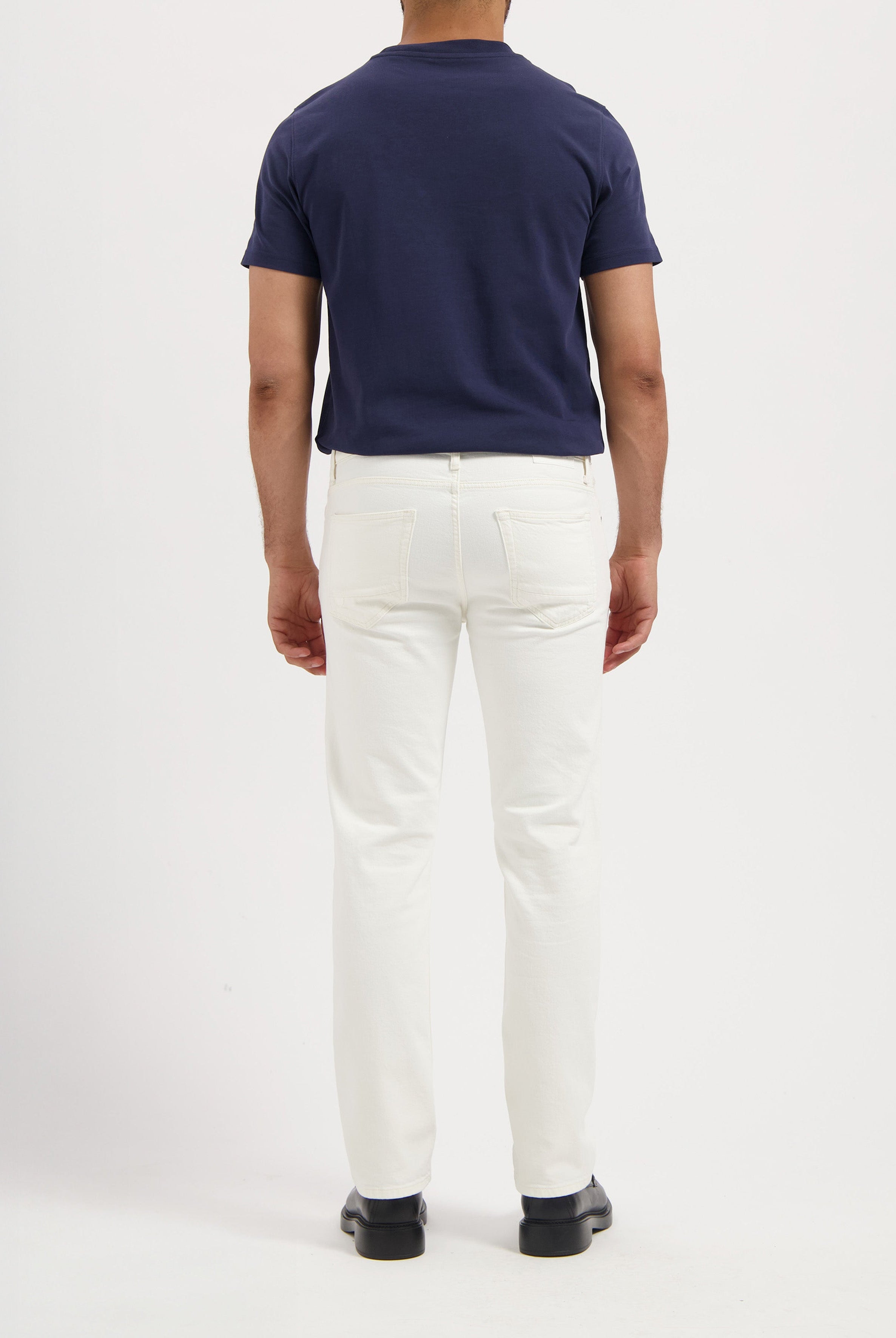 Sustainable MUD Jeans in dark indigo denim, paired with white sneakers, embodying ethical fashion.