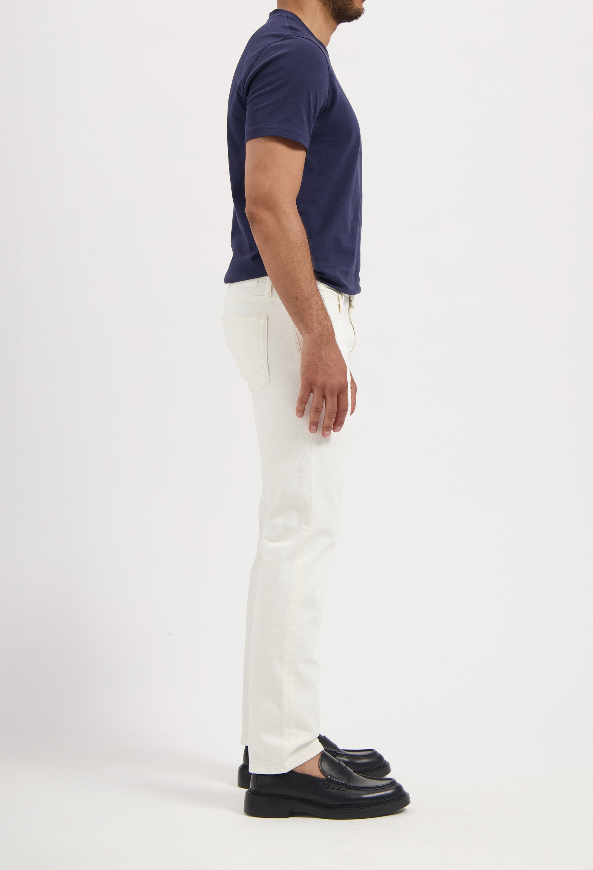 Sustainable MUD Jeans in light blue denim, worn with a white tank top and denim shorts, set in an outdoor setting.