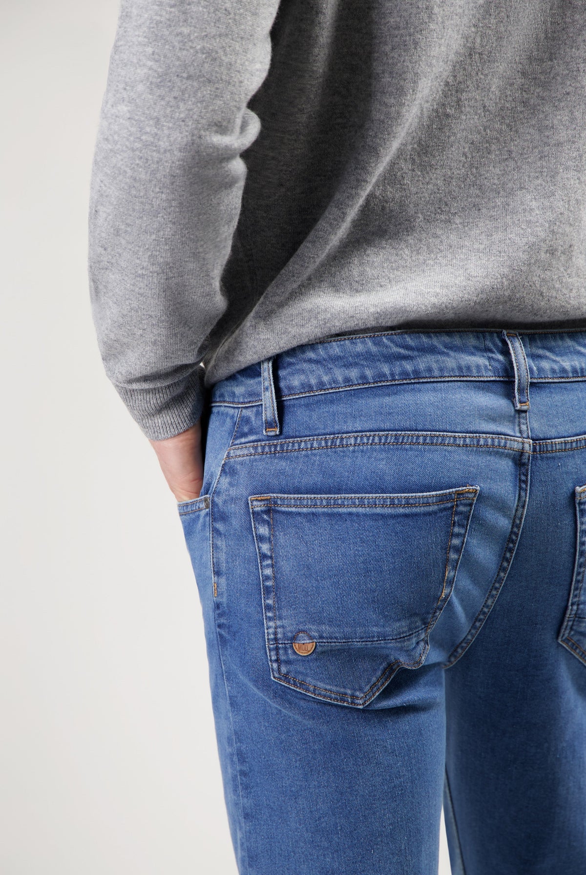 Sustainable MUD Jeans made from ethical organic cotton, light blue denim, styled with a cozy gray sweater.
