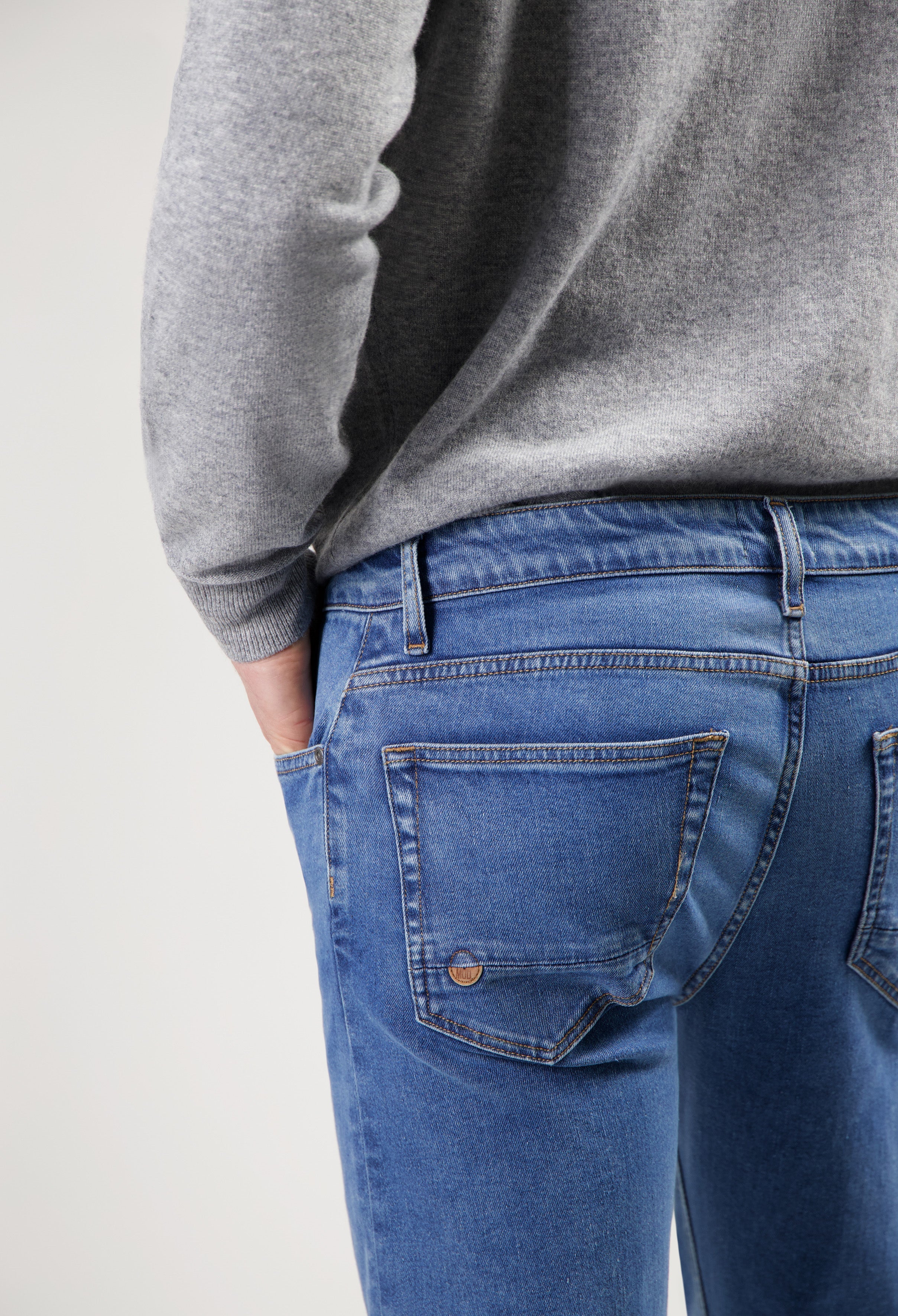 Sustainable MUD Jeans made from ethical organic cotton, light blue denim, styled with a cozy gray sweater.