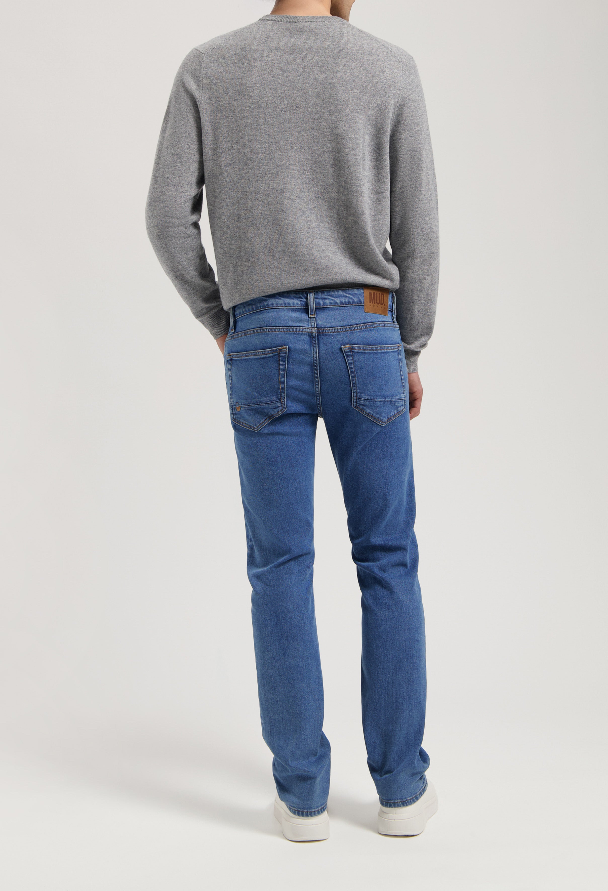 Sustainable MUD Jeans in classic blue denim, crafted from ethical materials, paired with a cozy gray sweater.