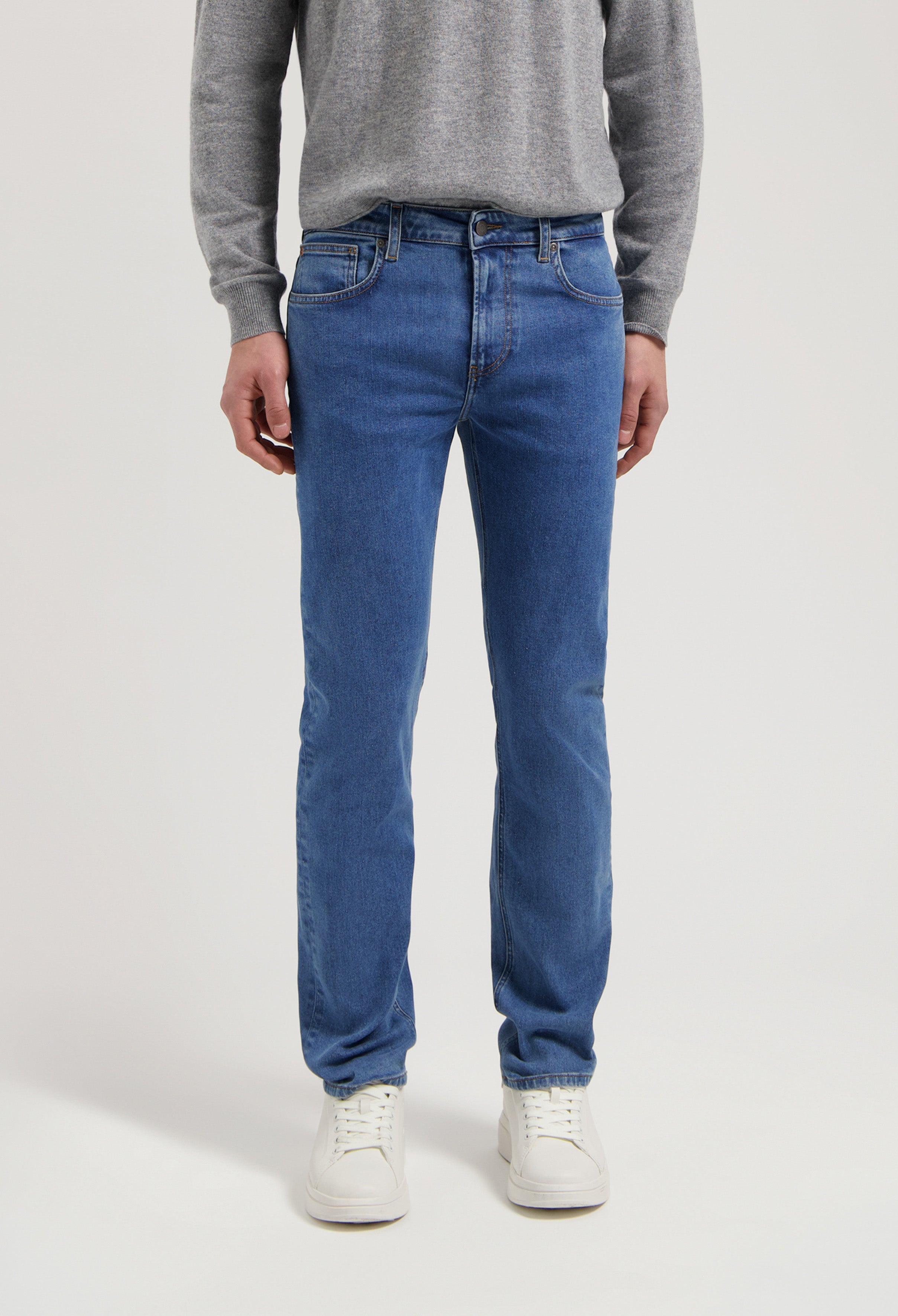 Sustainable MUD Jeans made from organic denim, featuring a classic fit in medium blue, paired with a gray sweater.