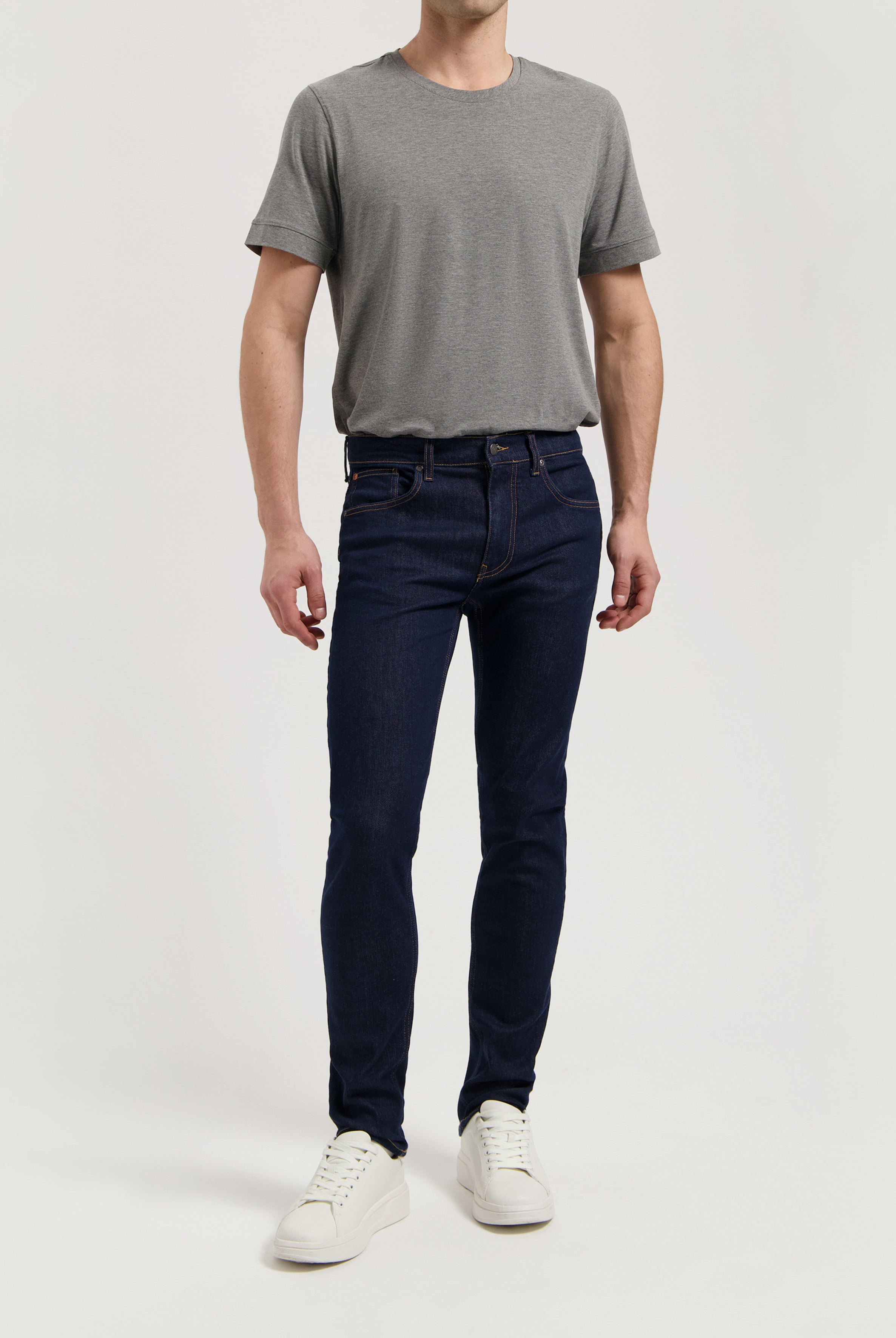 Sustainable MUD Jeans blue denim shorts styled with a white T-shirt and white sneakers for a casual look.