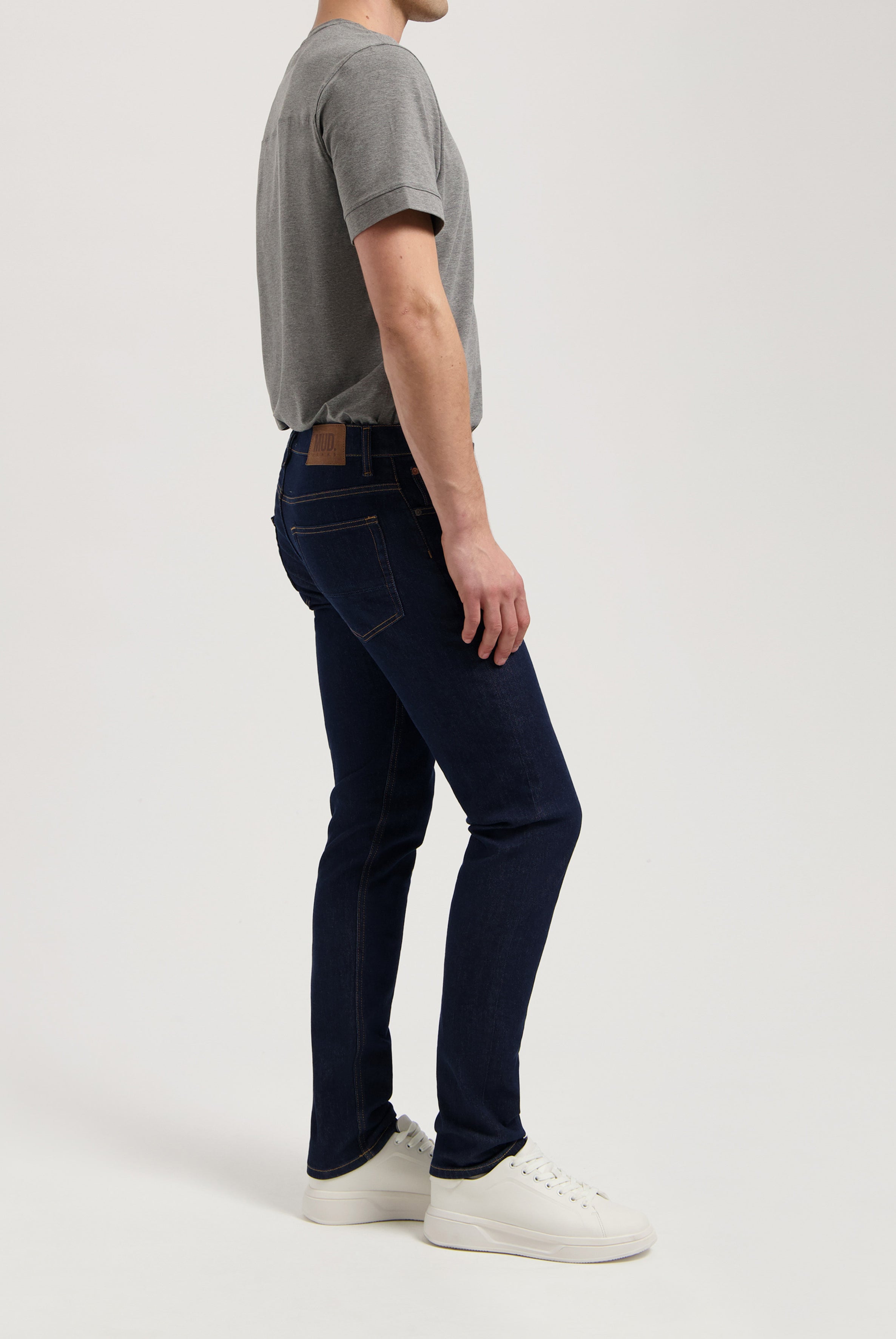 Sustainable MUD Jeans dark blue denim shorts, crafted ethically with organic cotton, paired with a white t-shirt and sneakers.