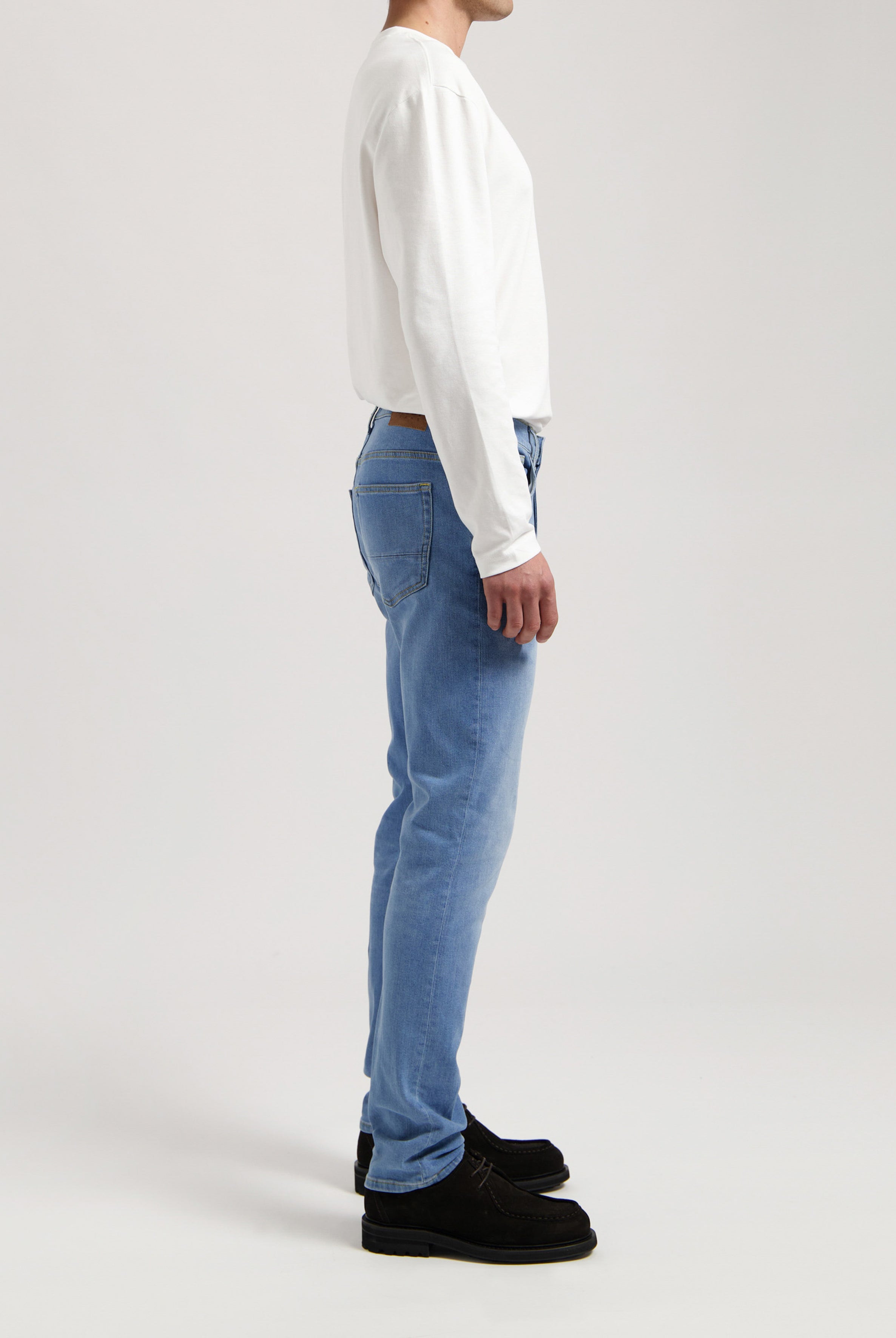 Sustainable MUD Jeans in deep blue denim, crafted ethically from organic cotton, paired with a gray sweater.