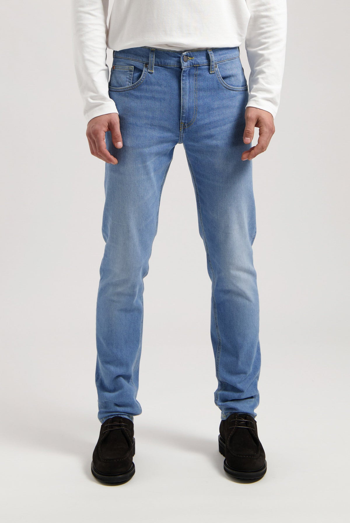 Sustainable MUD Jeans made from organic cotton, featuring classic light blue denim, paired with a gray t-shirt and white sneakers.